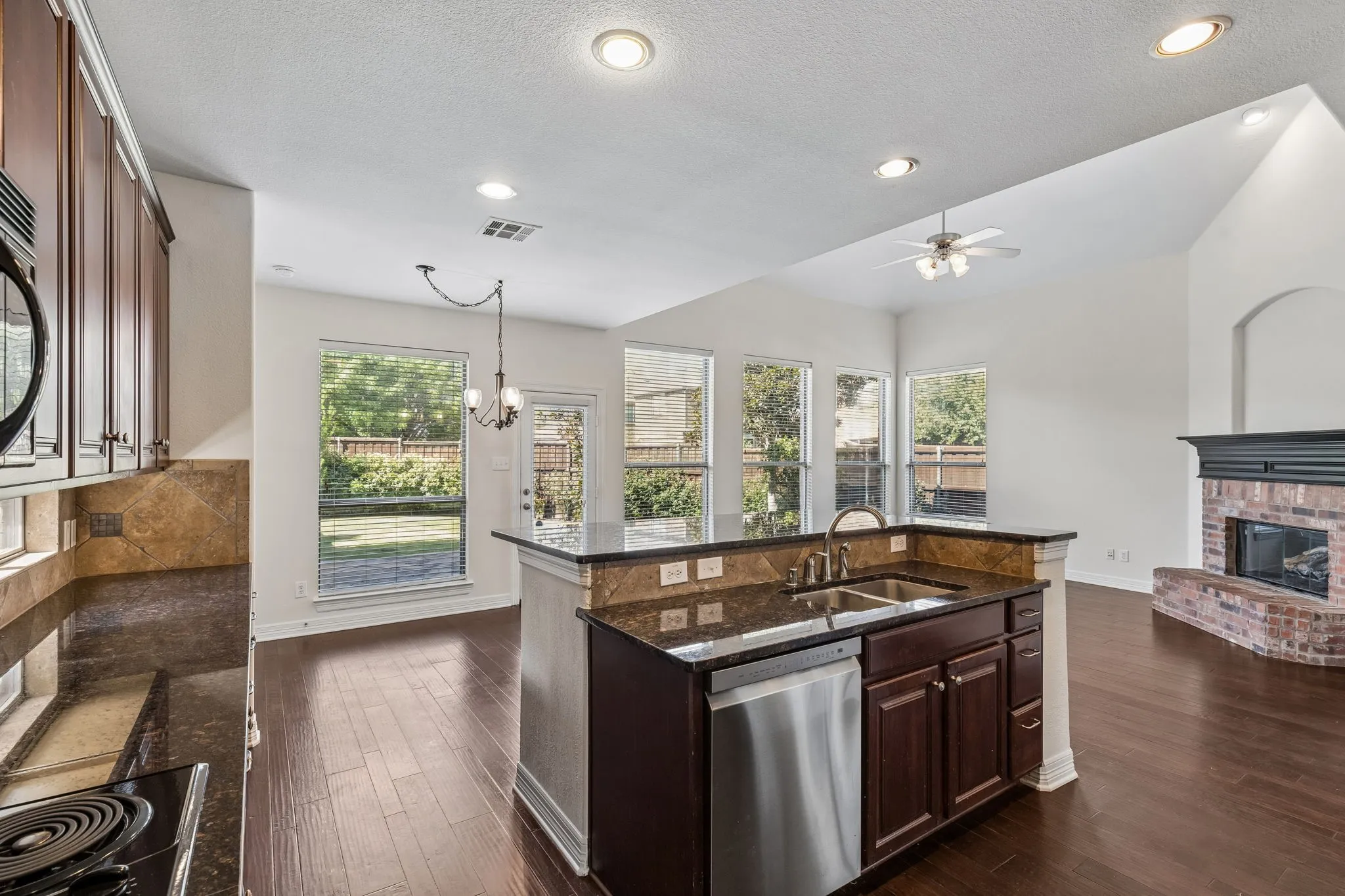 Kitchen with dark wood-finish cabinetry, built-in stainless steel appliances, and a central island featuring an undermount sink