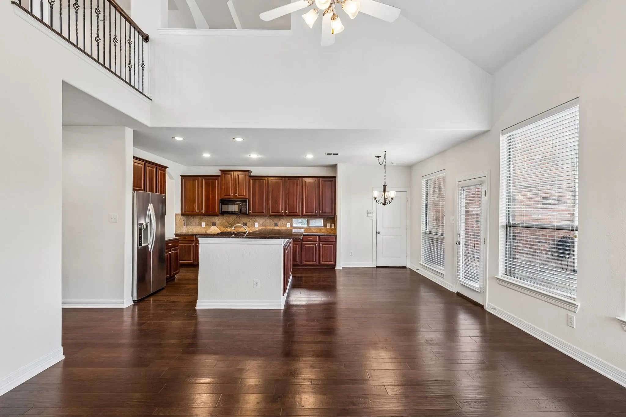 Expansive living area with wood-finish flooring, vaulted ceilings, and large windows