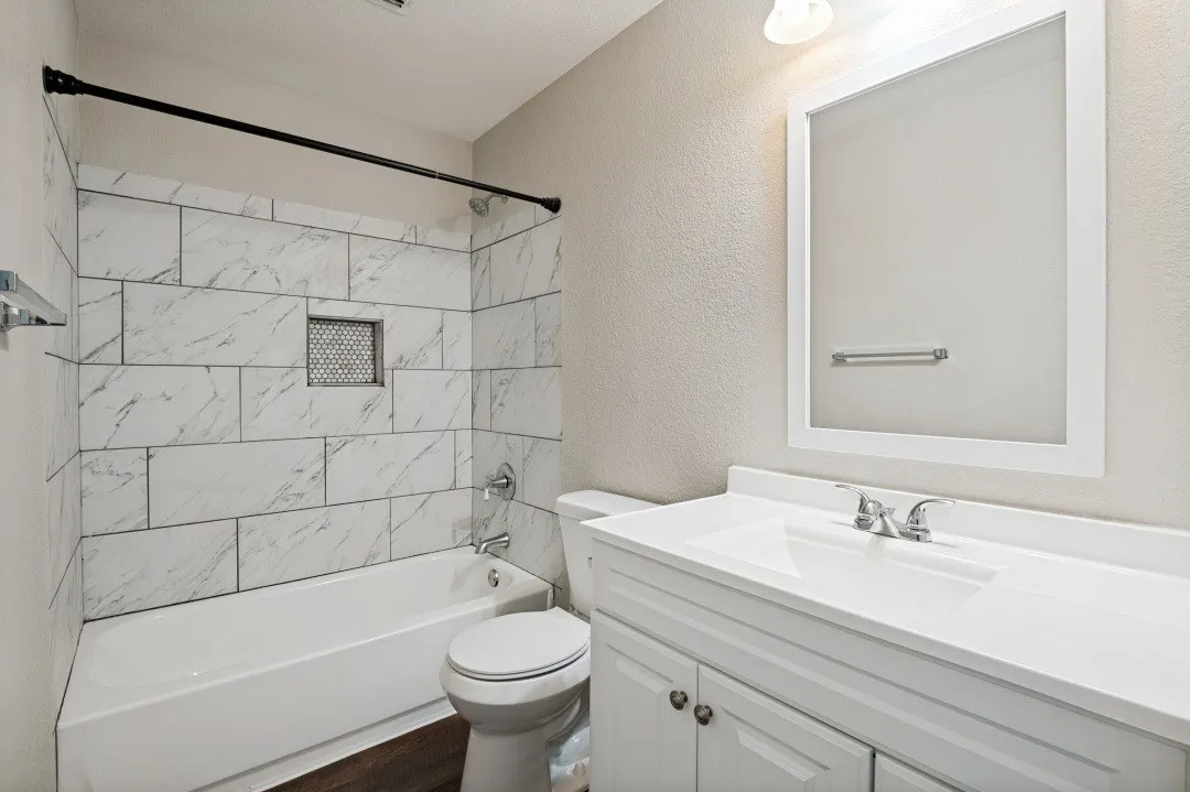 Bathroom featuring a white vanity with integrated sink, white framed mirror, and a tub/shower combination