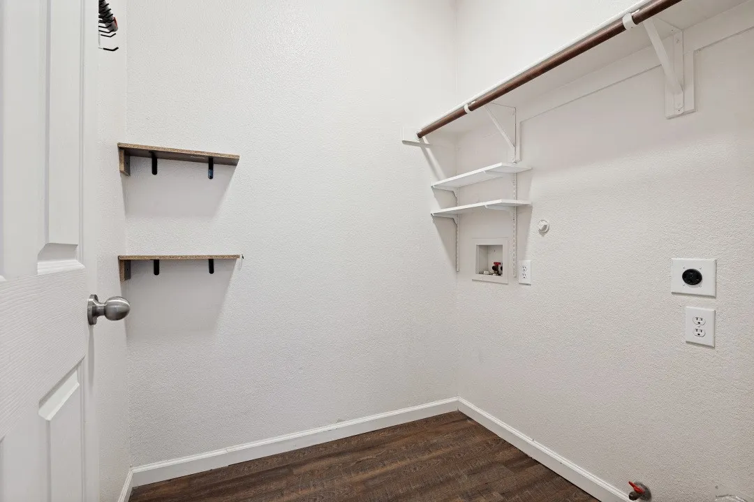 Dedicated utility area featuring wood-finish flooring and white baseboards