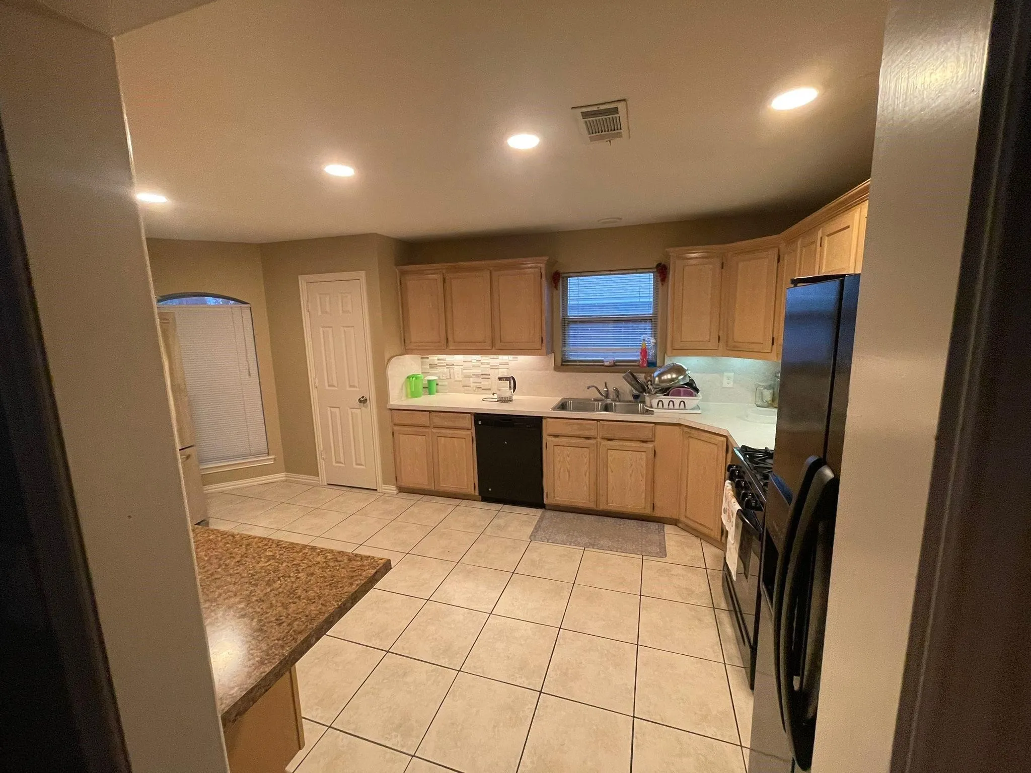 Kitchen featuring recessed lighting, a stone-look countertop, light wood-finish cabinetry, a subway tile backsplash, and ceramic tile flooring