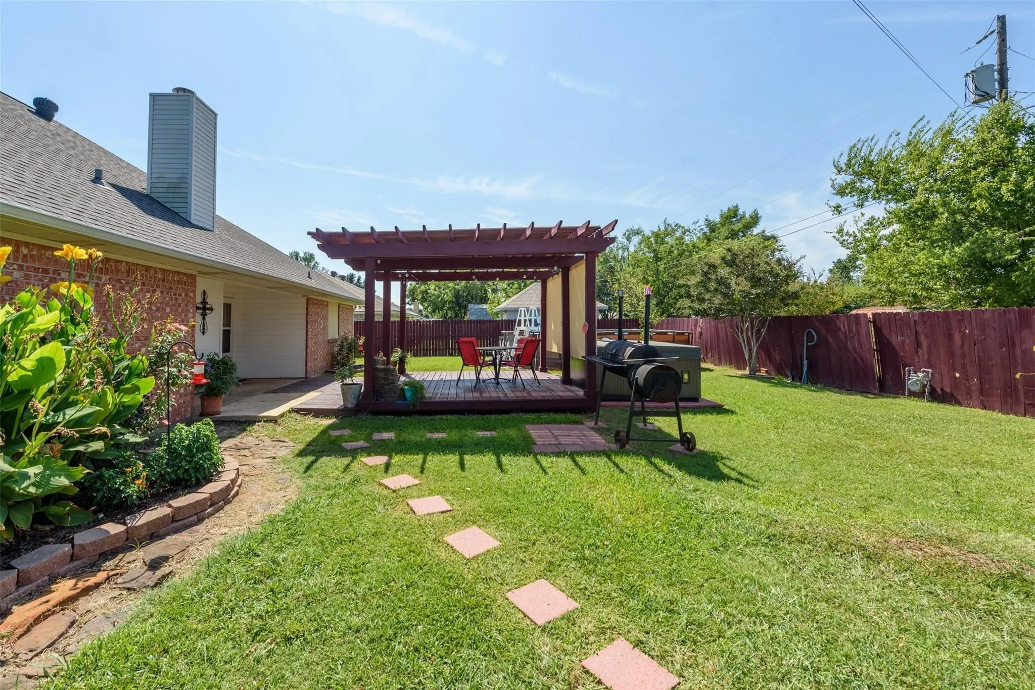 Expansive backyard featuring a pergola-covered deck, a brick exterior, a large green lawn, and a privacy fence