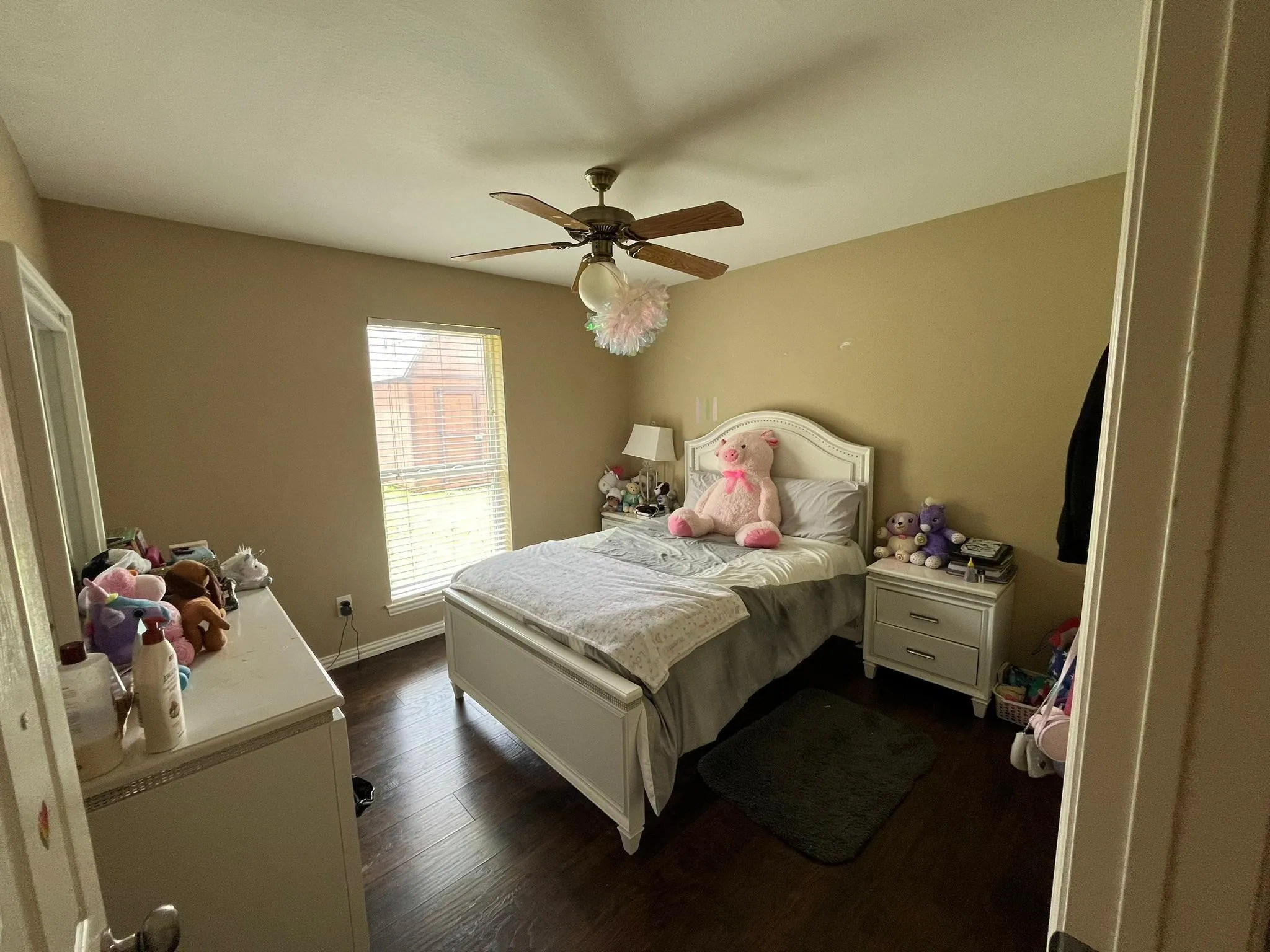 Spacious room featuring wood-finish flooring, a ceiling fan with light fixture, and a window with blinds