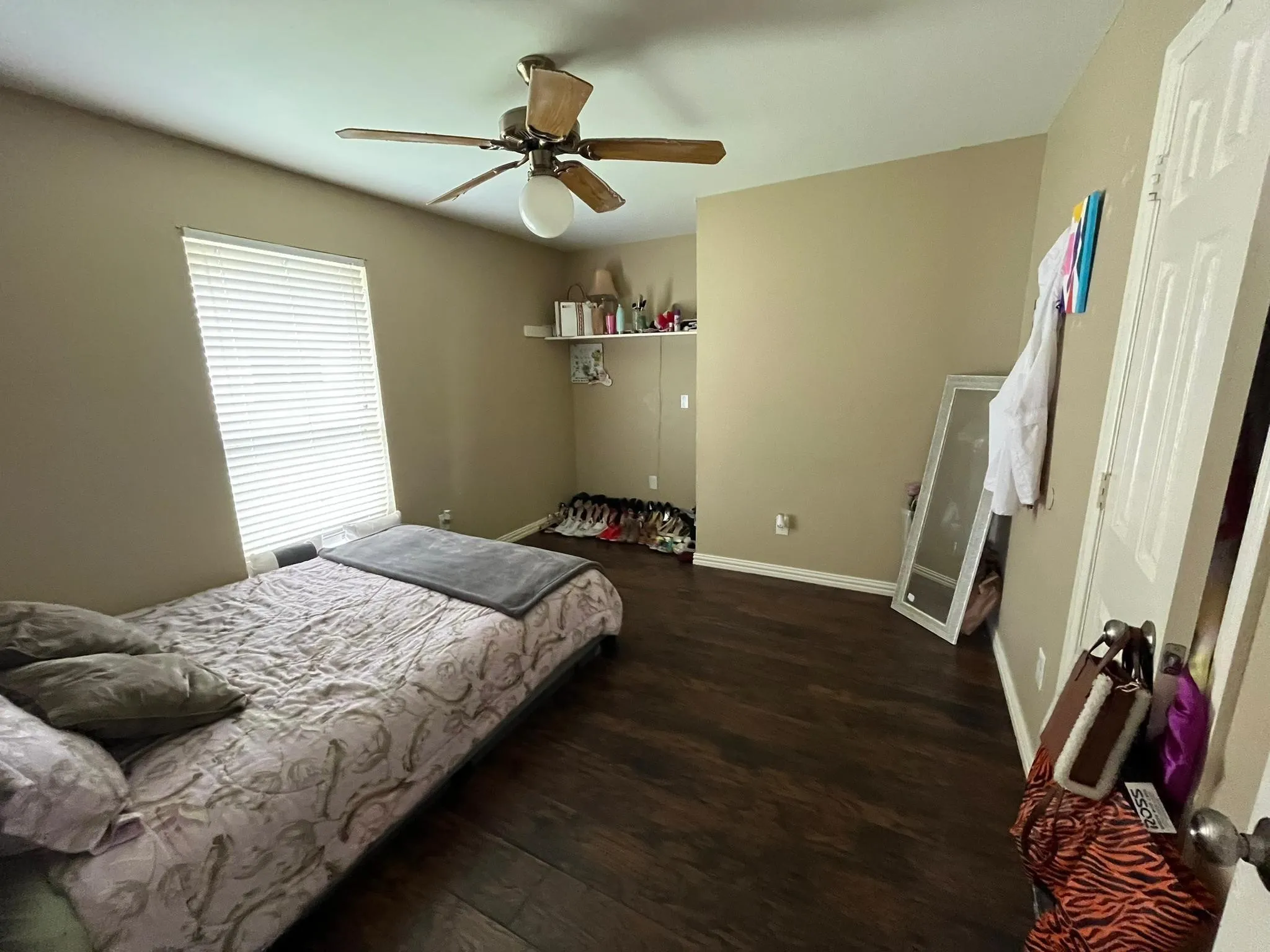 Spacious room with dark wood-finish flooring, neutral wall tones, and a ceiling fan with integrated lighting