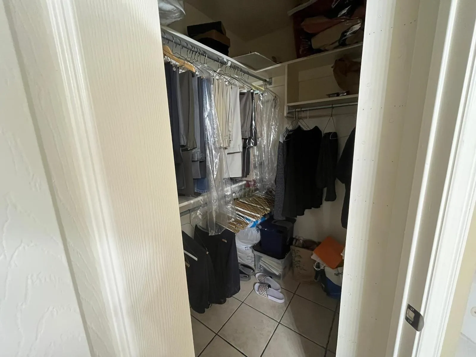 Walk-in closet featuring white wire shelving, multiple hanging rods, and light-toned tile flooring