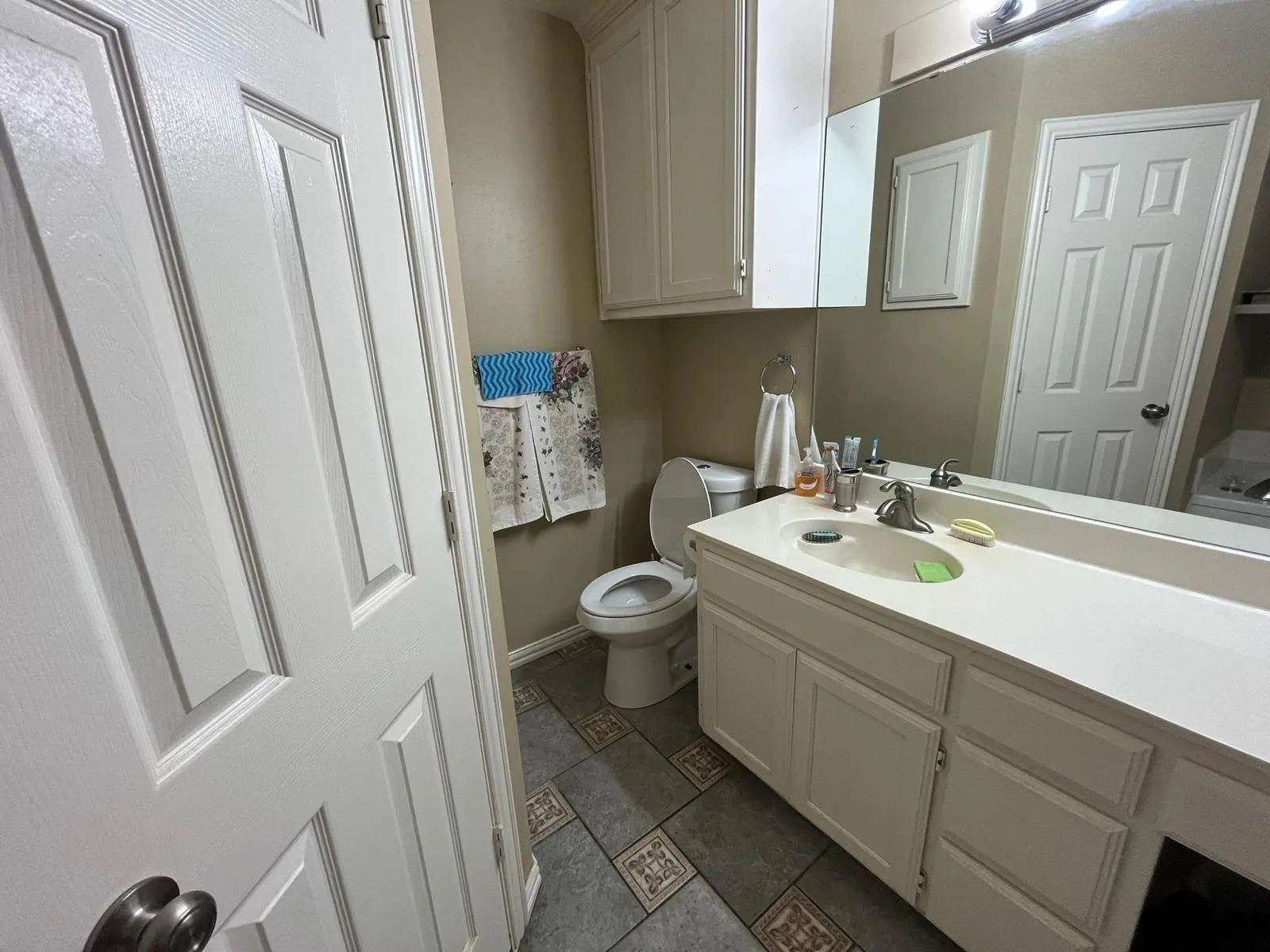 Bathroom featuring a white vanity with integrated sink, chrome faucet, and expansive wall-mounted mirror