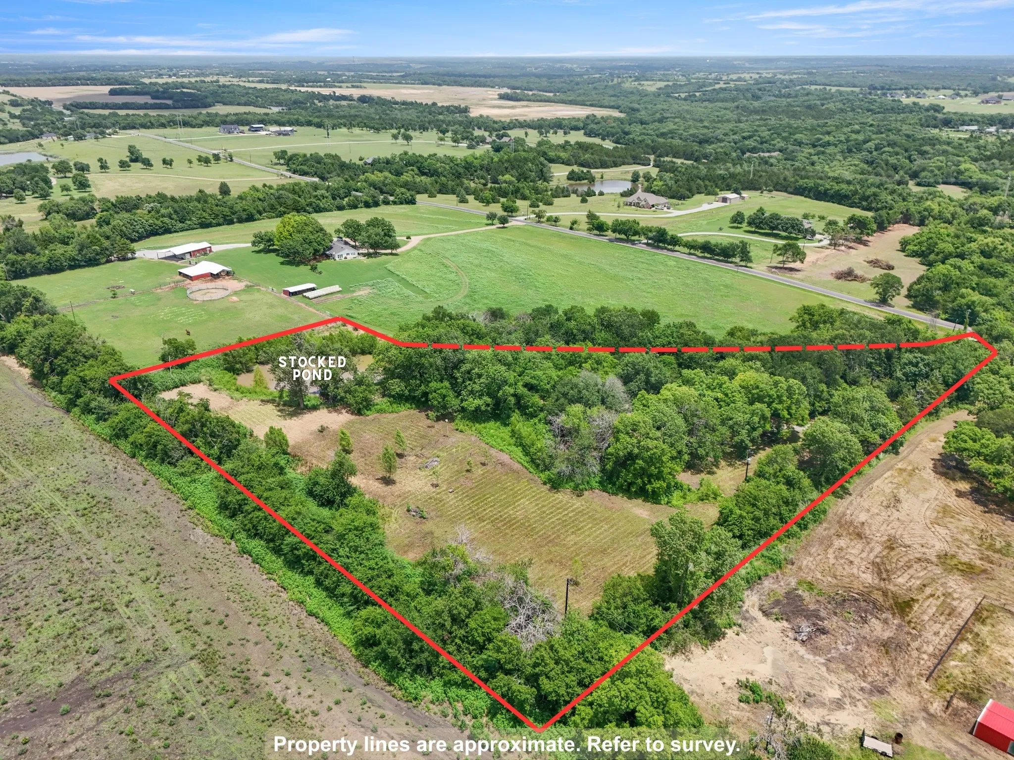 Elevated aerial view of the property with approximate boundaries, mature trees, open areas, and stocked pond.