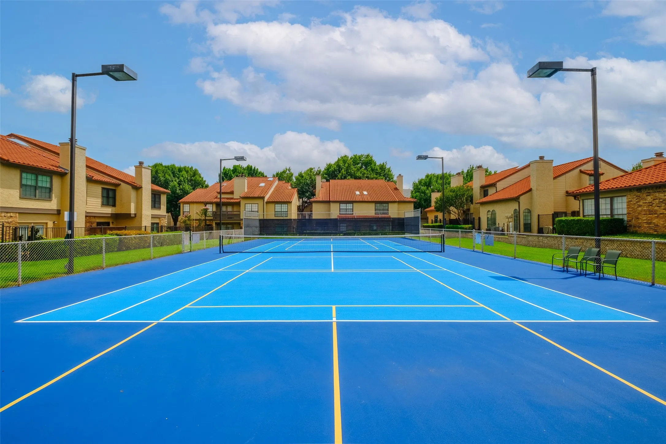 Tennis and pickleball court with LED sports lighting, and a fenced enclosure — a standout amenity right within the community.