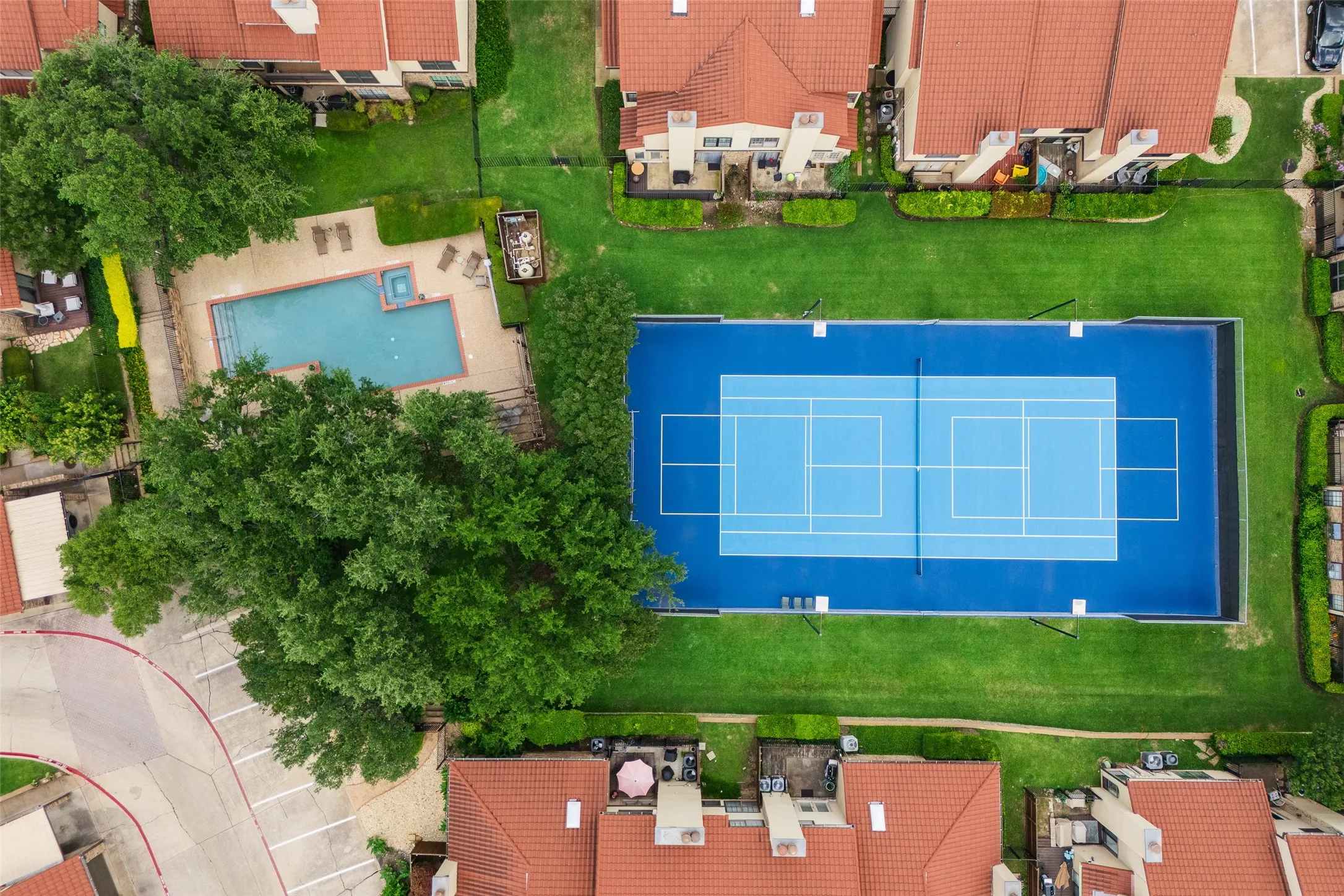 Overhead aerial of La Mirada's community amenities — a sparkling pool with adjacent spa and sun deck, and a full tennis/pickleball court surrounded by manicured greenspace.