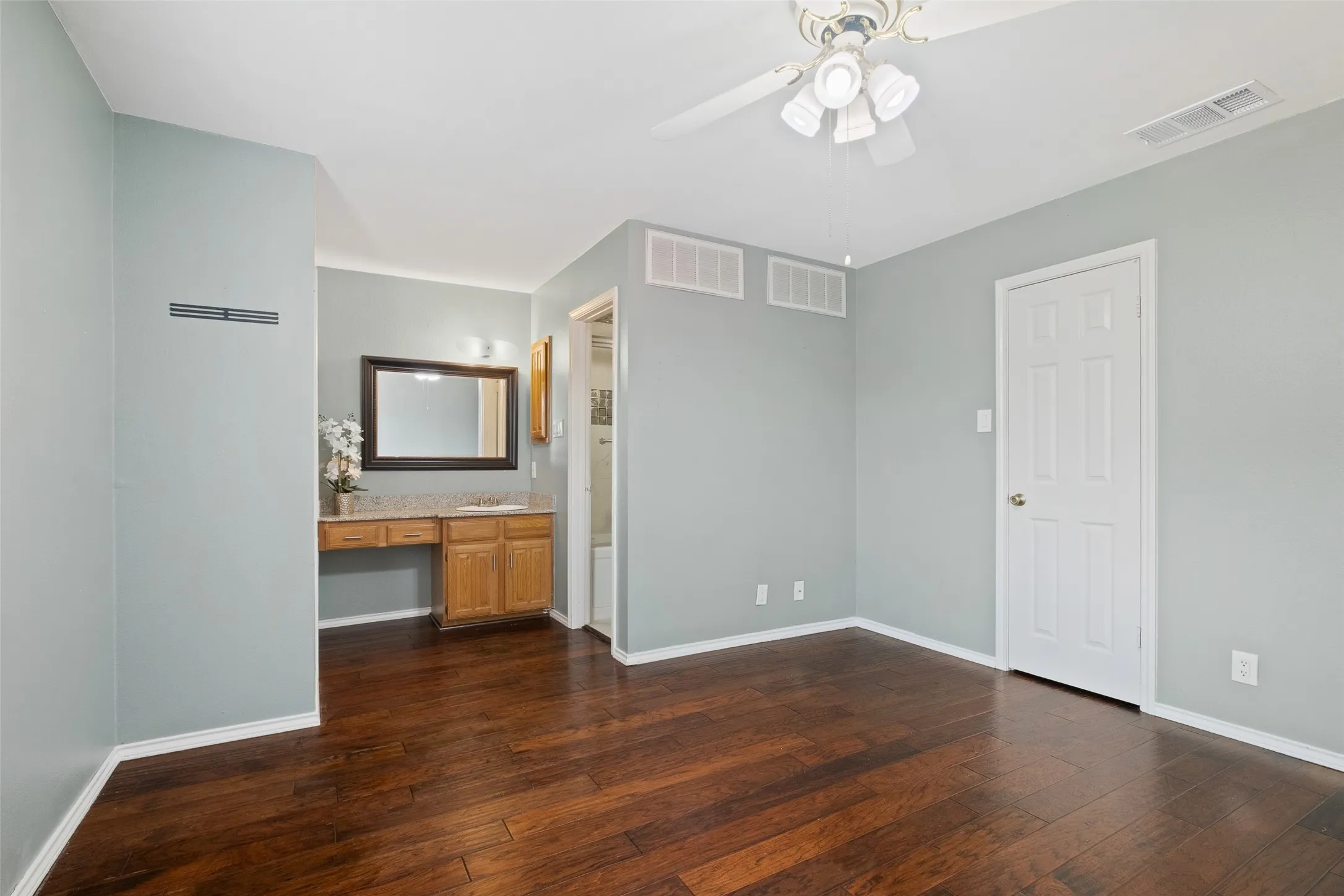 Secondary bedroom showing the built-in vanity with granite countertop, closet, and en-suite bath access — a functional layout that offers privacy and convenience for guests or a second occupant.
