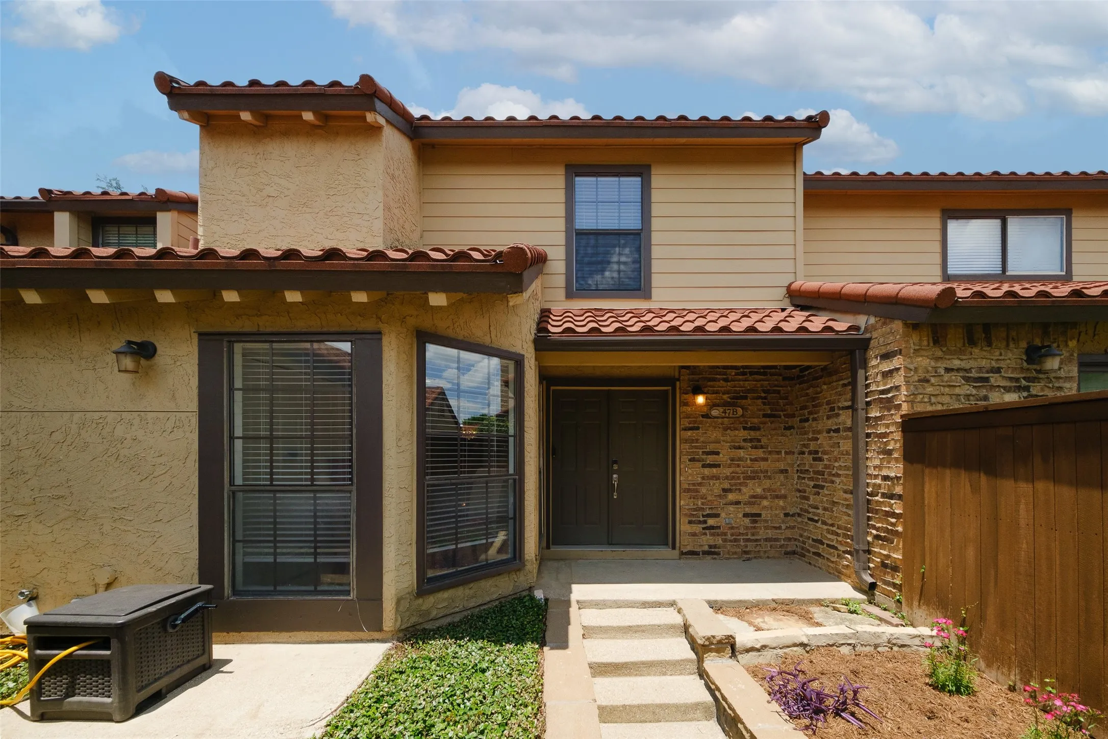 Front entry featuring brick accent columns, clay tile roof line, covered entry porch, and lush landscaping — classic La Mirada character.