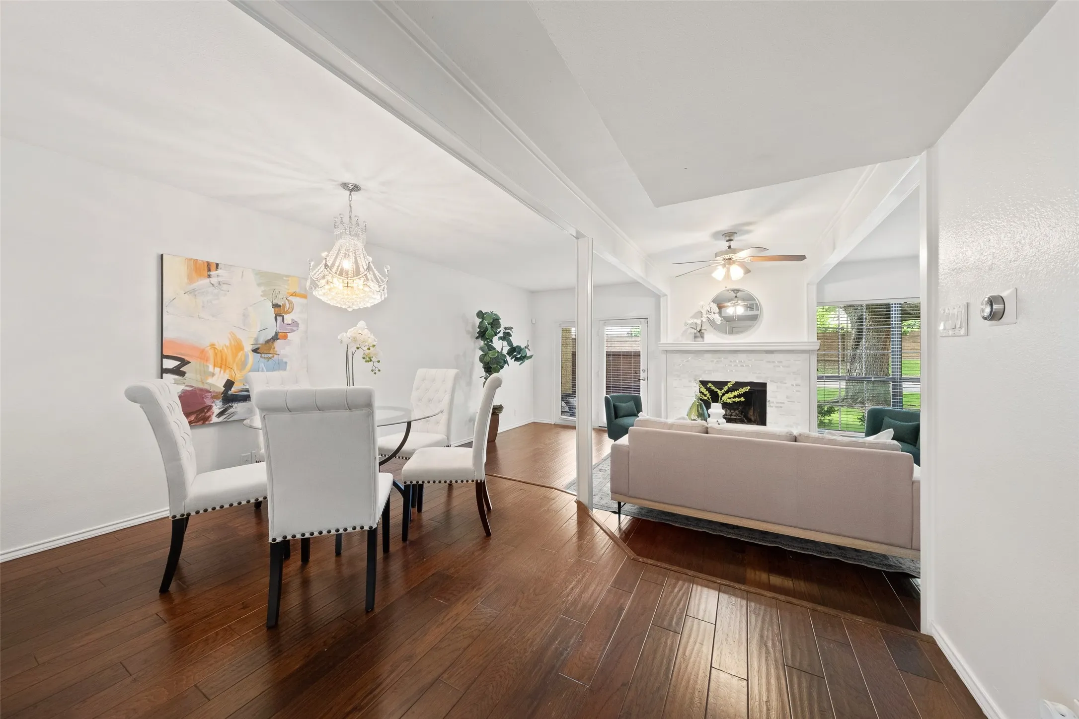 Wide view of the dining and living areas showing the seamless flow of the main level, rich hardwood floors throughout, and the fireplace visible from both spaces.