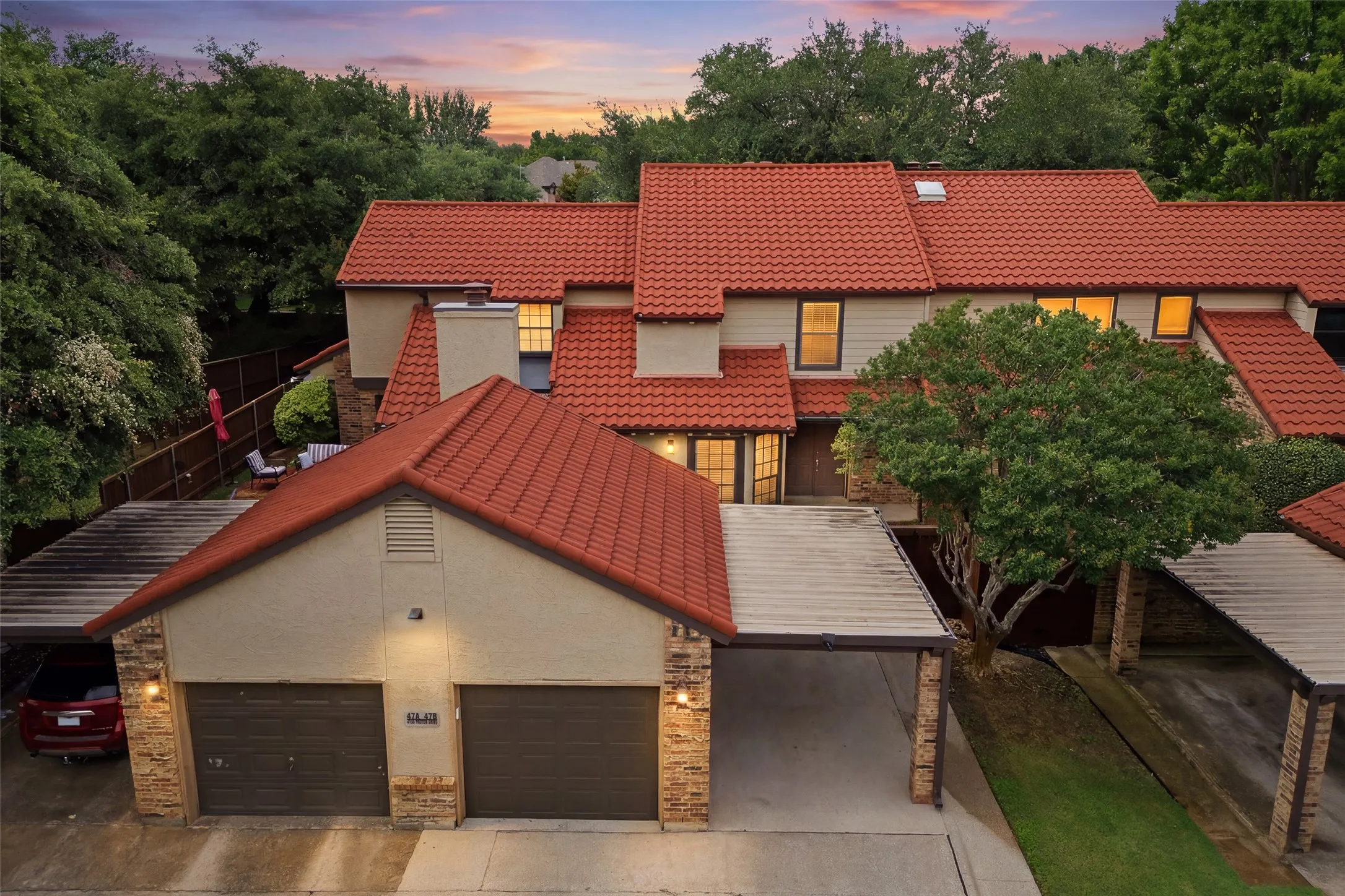 Stunning twilight aerial view of 4130 Proton Dr. #47B, showcasing the signature clay tile roof, one-car garage, and covered parking for an additional vehicle.