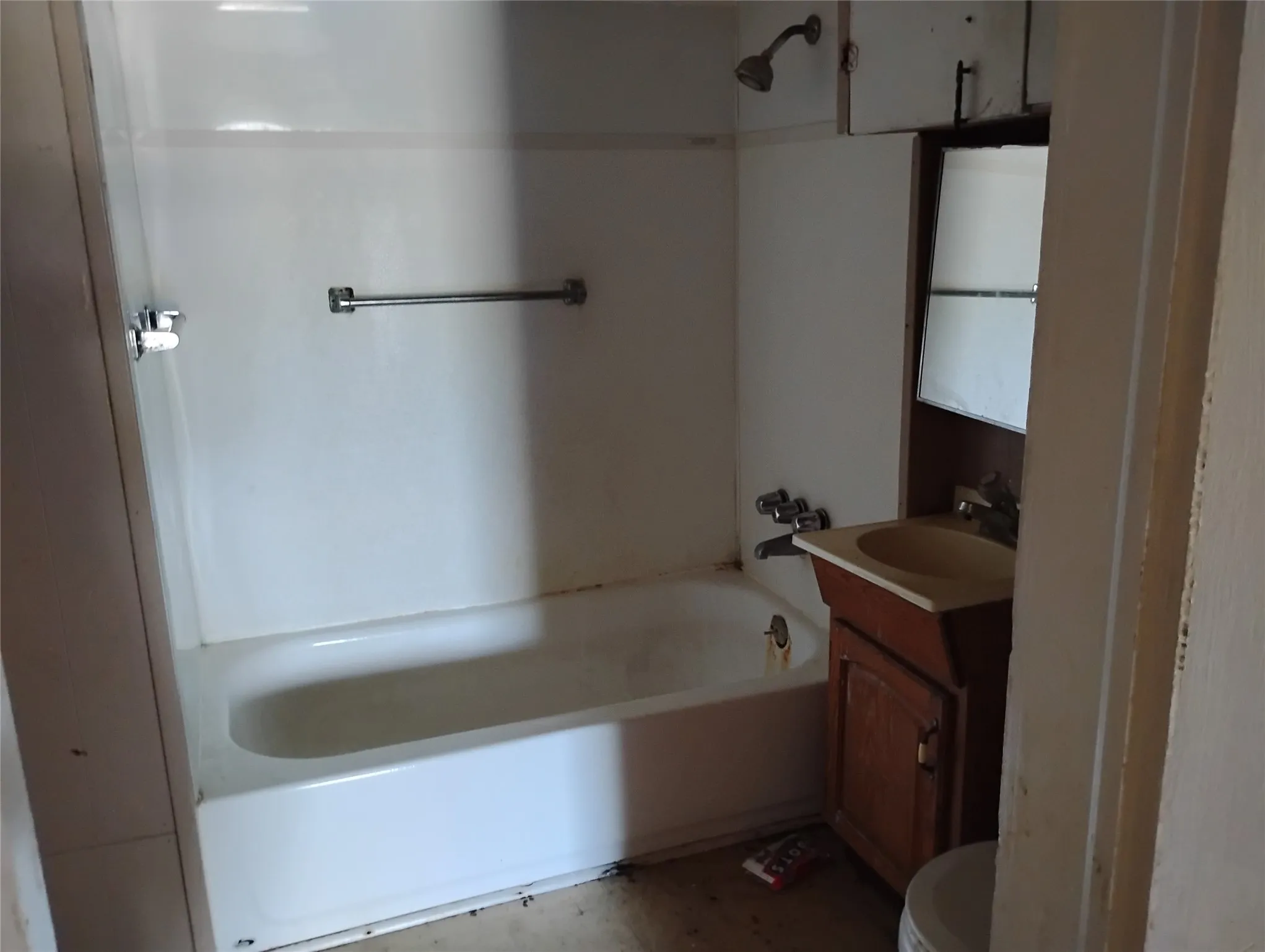 Bathroom featuring a white bathtub with a shower head, a single vanity with a basin sink, and a mirrored cabinet
