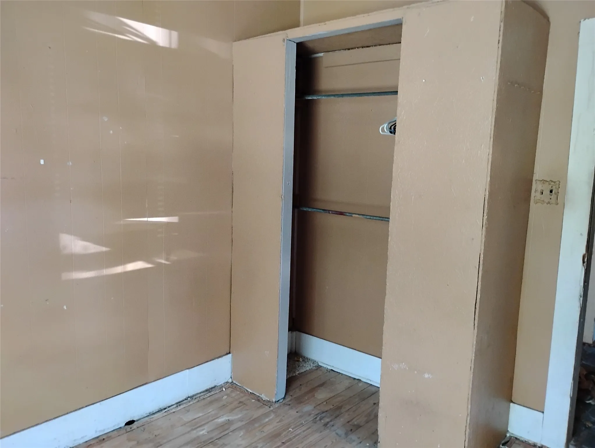 Built-in closet with two storage rods and light wood-finish flooring