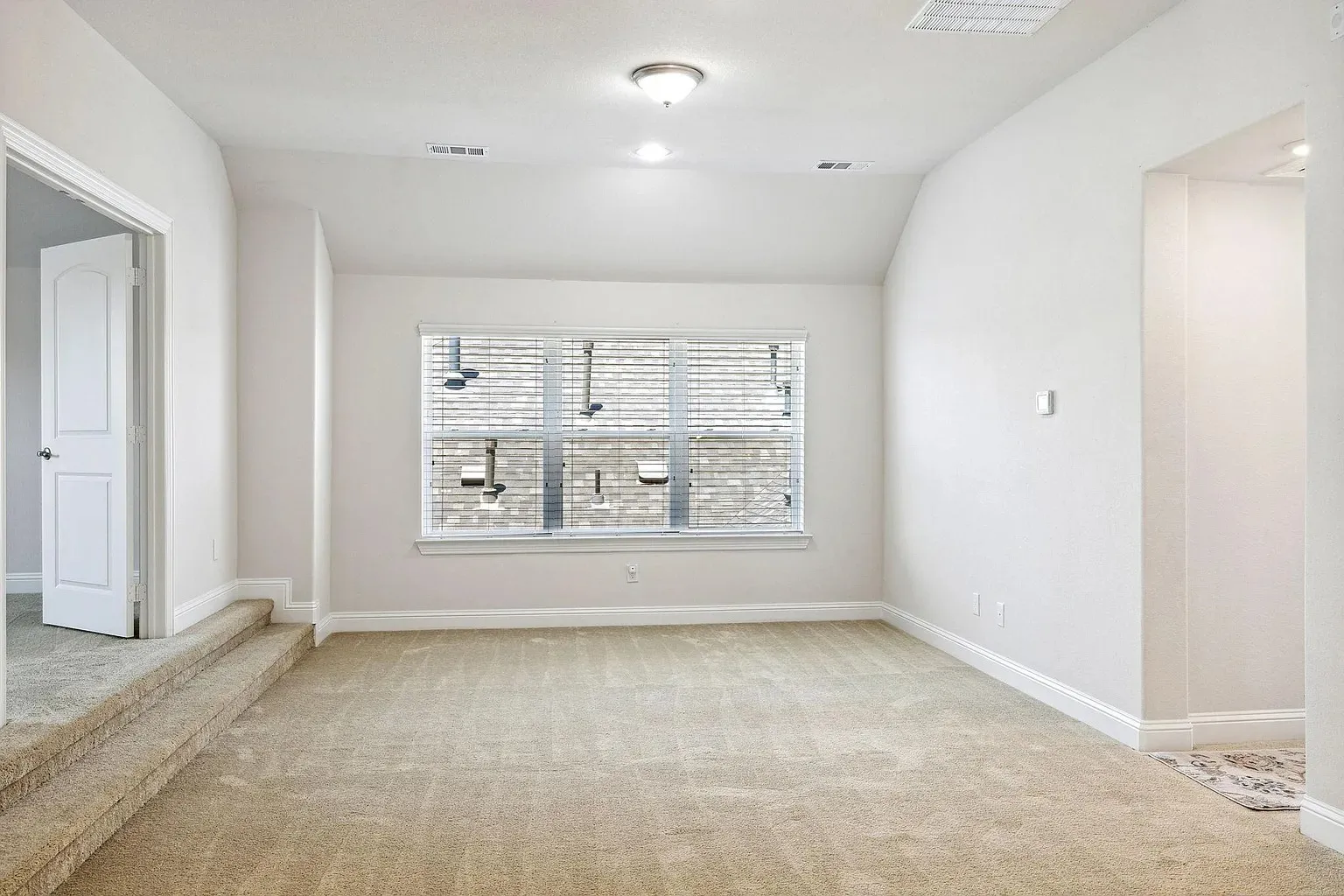 Carpeted room featuring a double-stepped entry, a single window with blinds, recessed lighting, and a white interior door