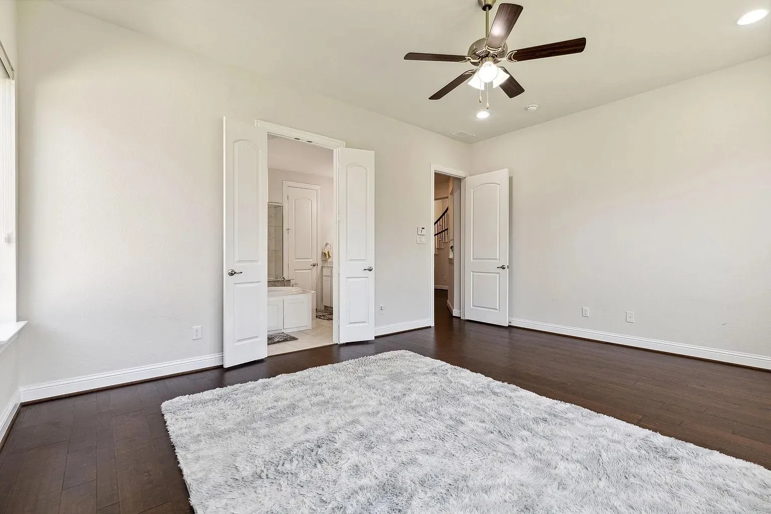 Spacious interior room featuring dark wood-finish flooring and light wall finishes