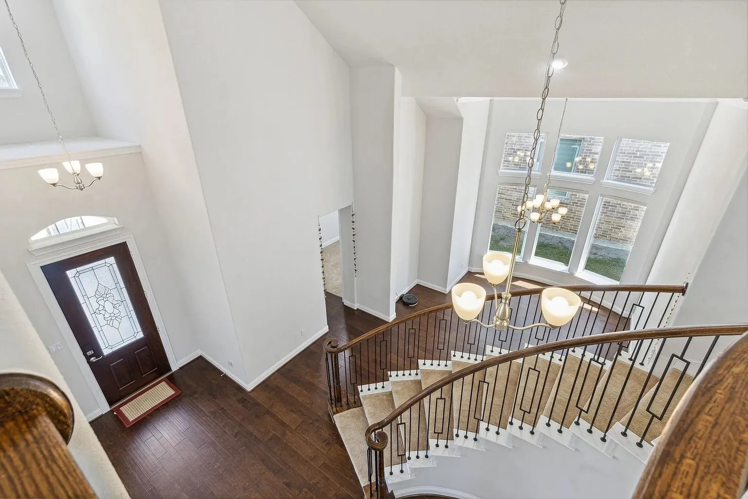 Two-story entryway featuring a curved staircase with metal spindles and wood handrails