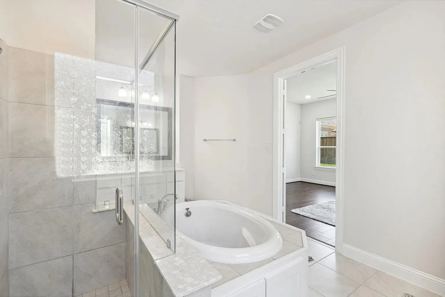 Bathroom featuring a frameless glass shower enclosure, a built-in soaking tub with a tiled surround, a vanity with a large mirror, and recessed lighting