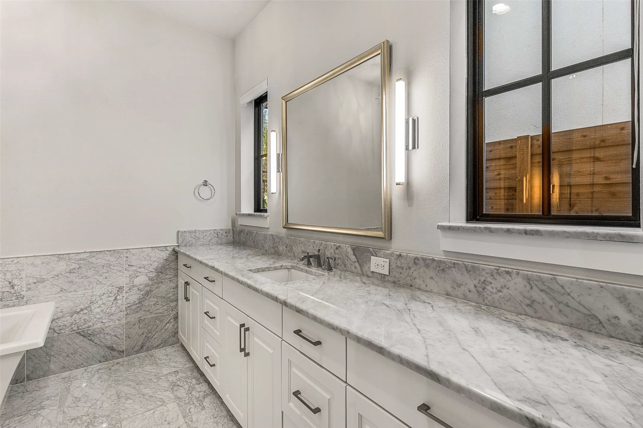 Double vanity featuring a light-toned countertop, integrated sink, and white cabinetry with dark hardware