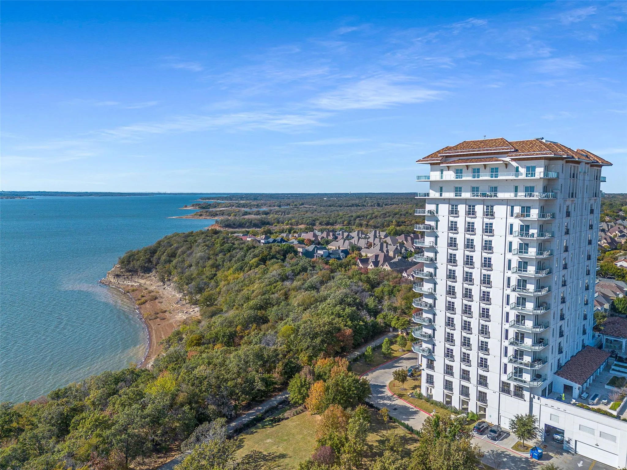 Waterfront high-rise building featuring multiple levels of private balconies with glass railings