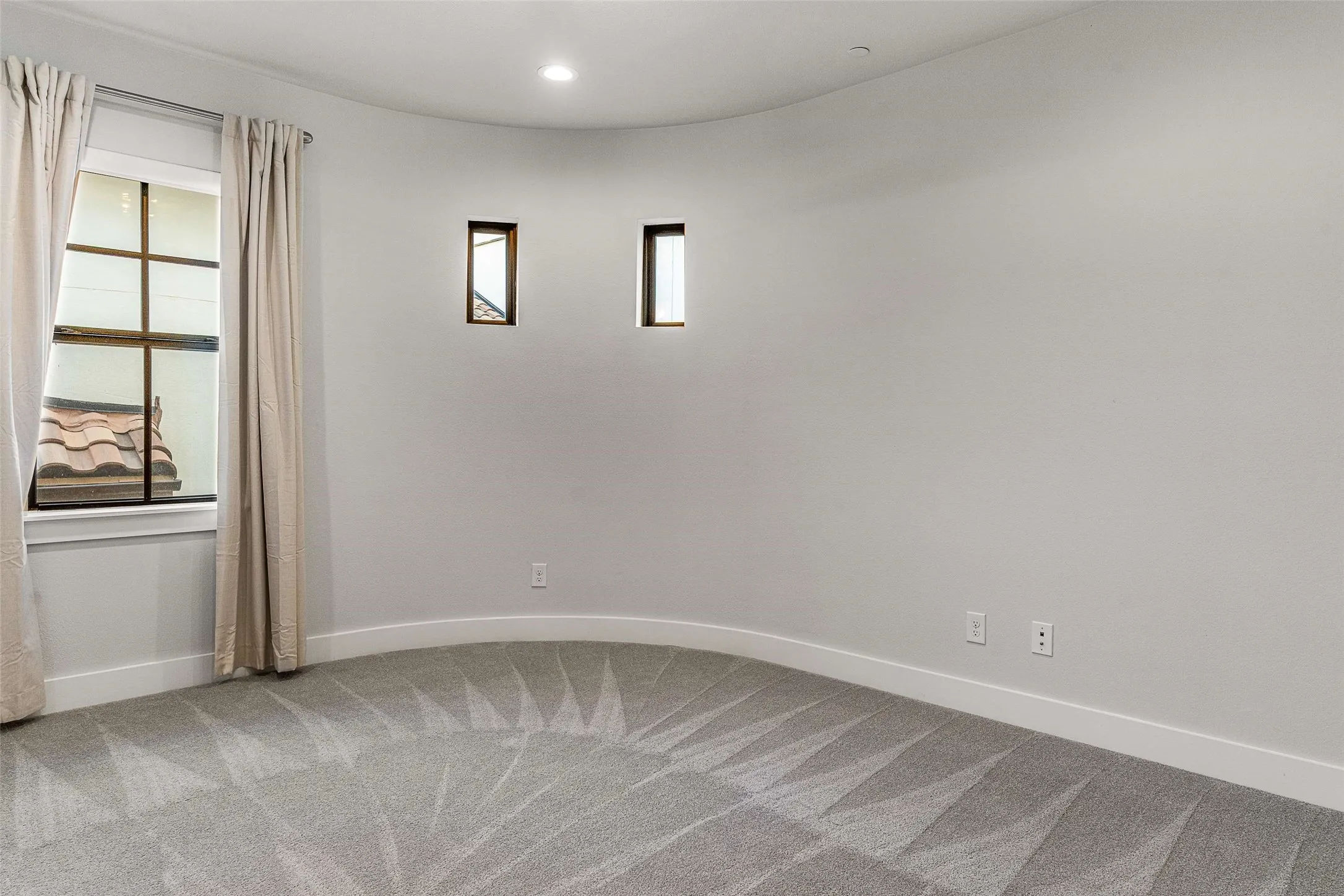 Room featuring a curved wall, geometric pattern carpet, recessed lighting, and a large window with white trim