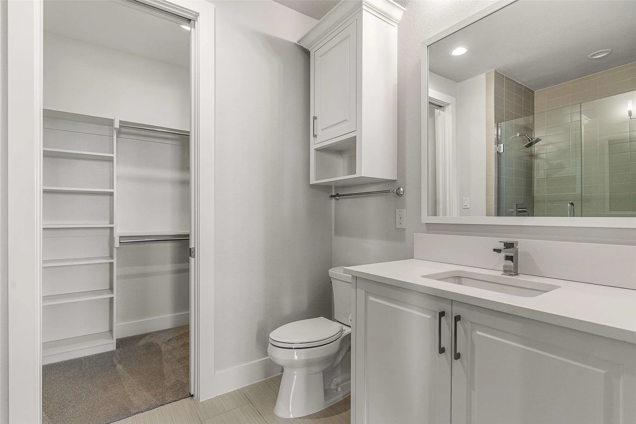 Contemporary bathroom featuring a white vanity with integrated sink, chrome faucet, and expansive wall mirror
