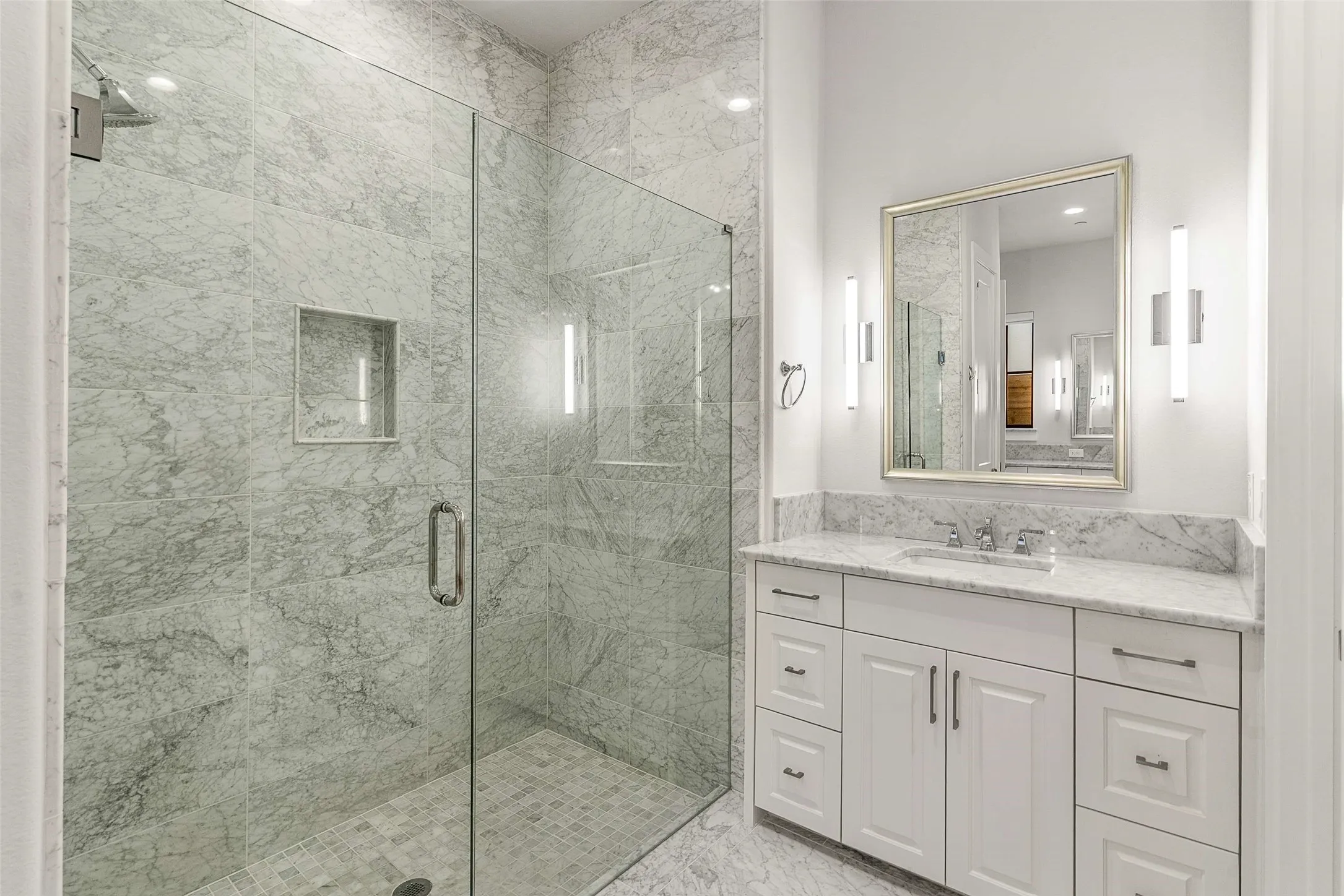 Spacious bathroom featuring a glass-enclosed shower with full-height stone tile surround and built-in shower niche