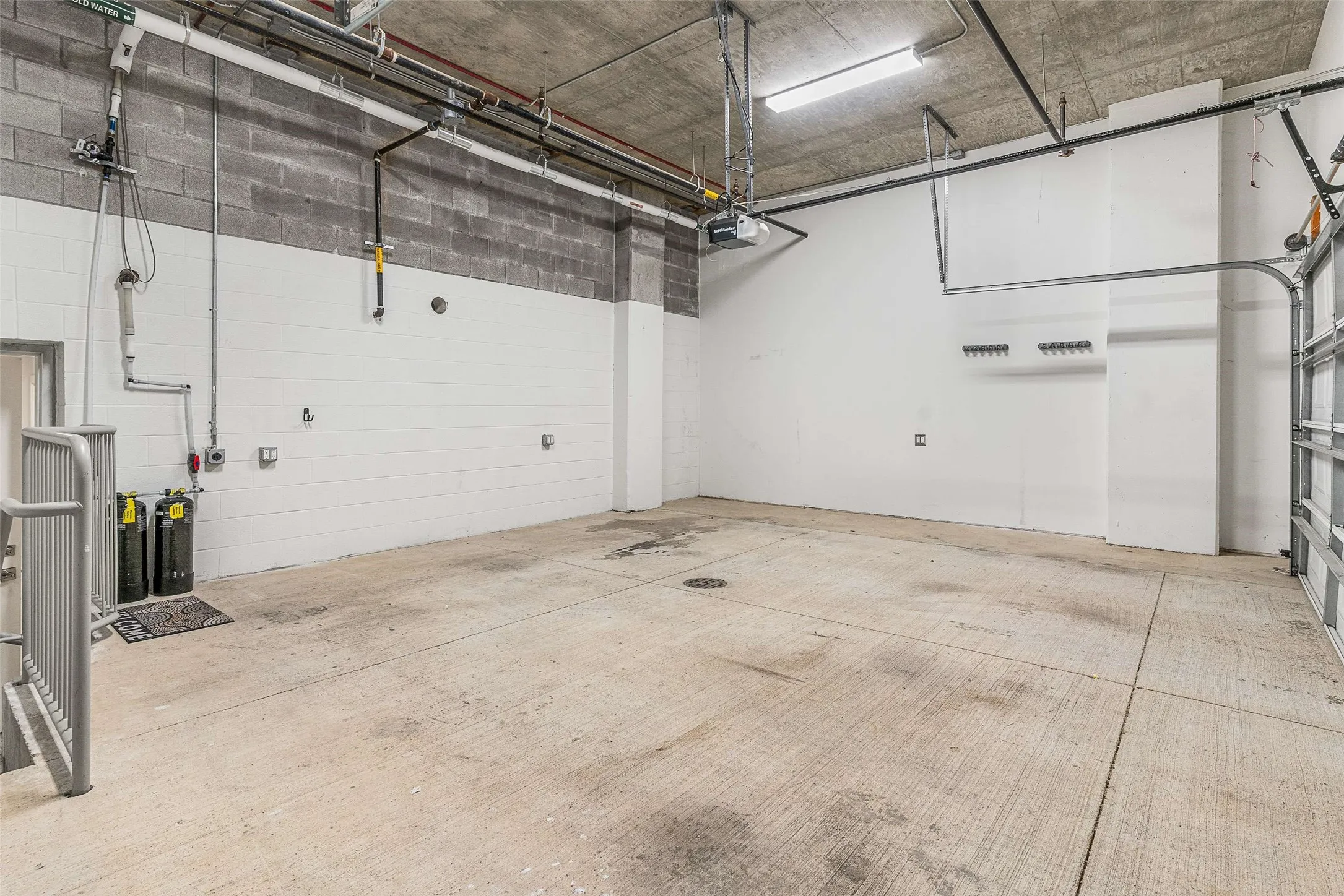 Spacious garage with concrete flooring, block and painted walls, and an exposed concrete ceiling