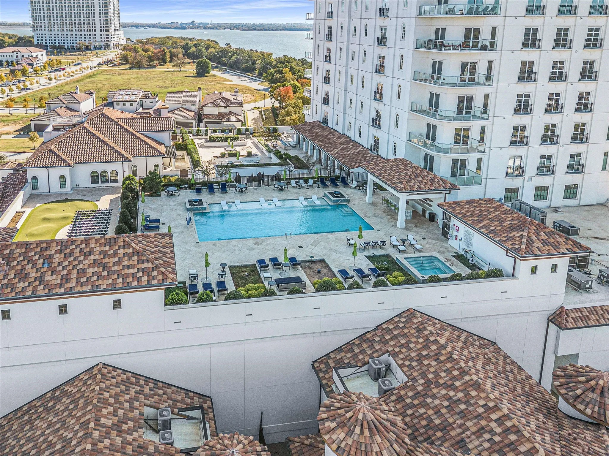 Expansive outdoor amenity deck featuring a large swimming pool, spa, and covered lounge areas