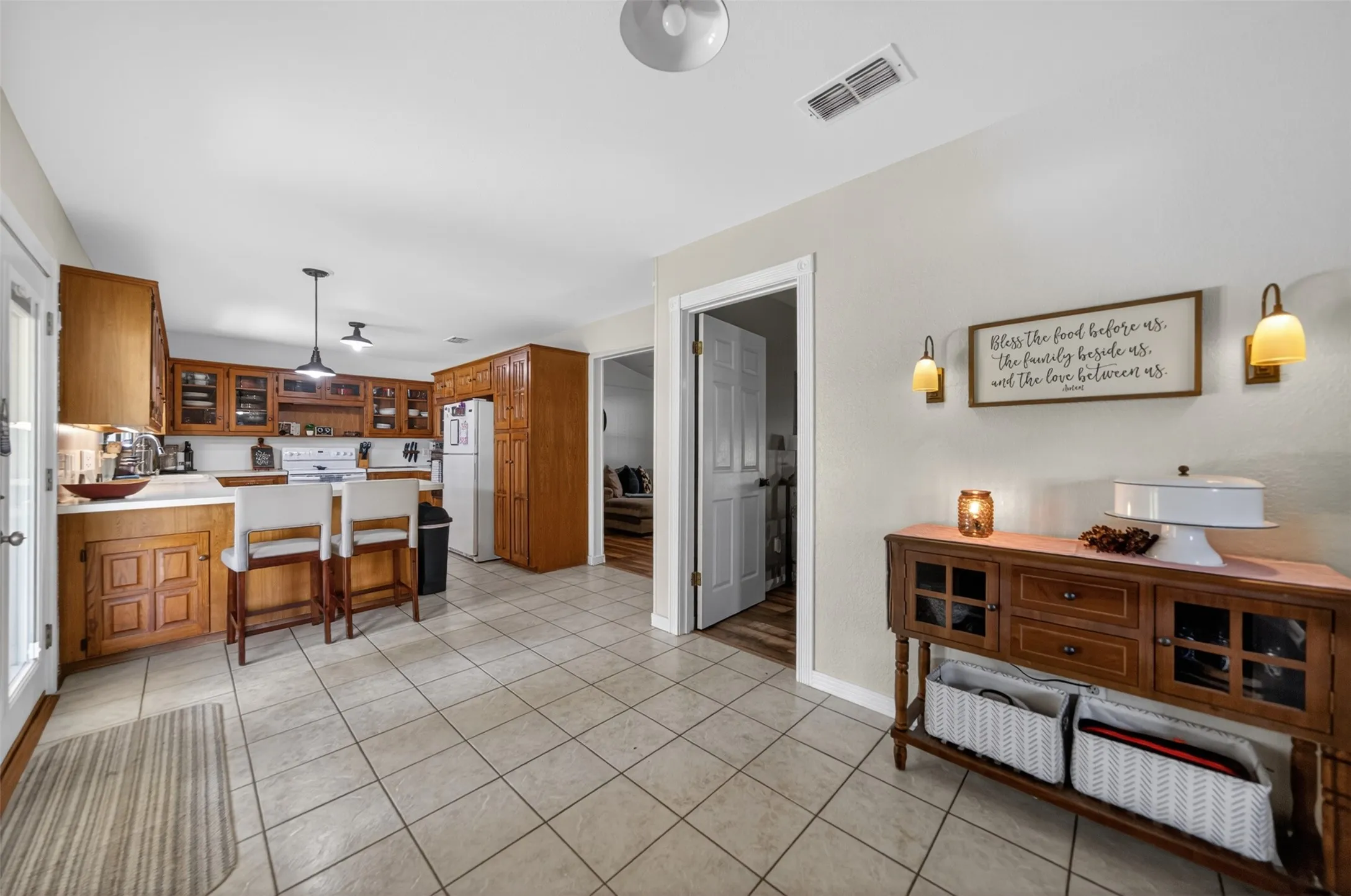 Kitchen featuring wood cabinetry with glass-front uppers, white countertops, tile flooring, and a peninsula with seating