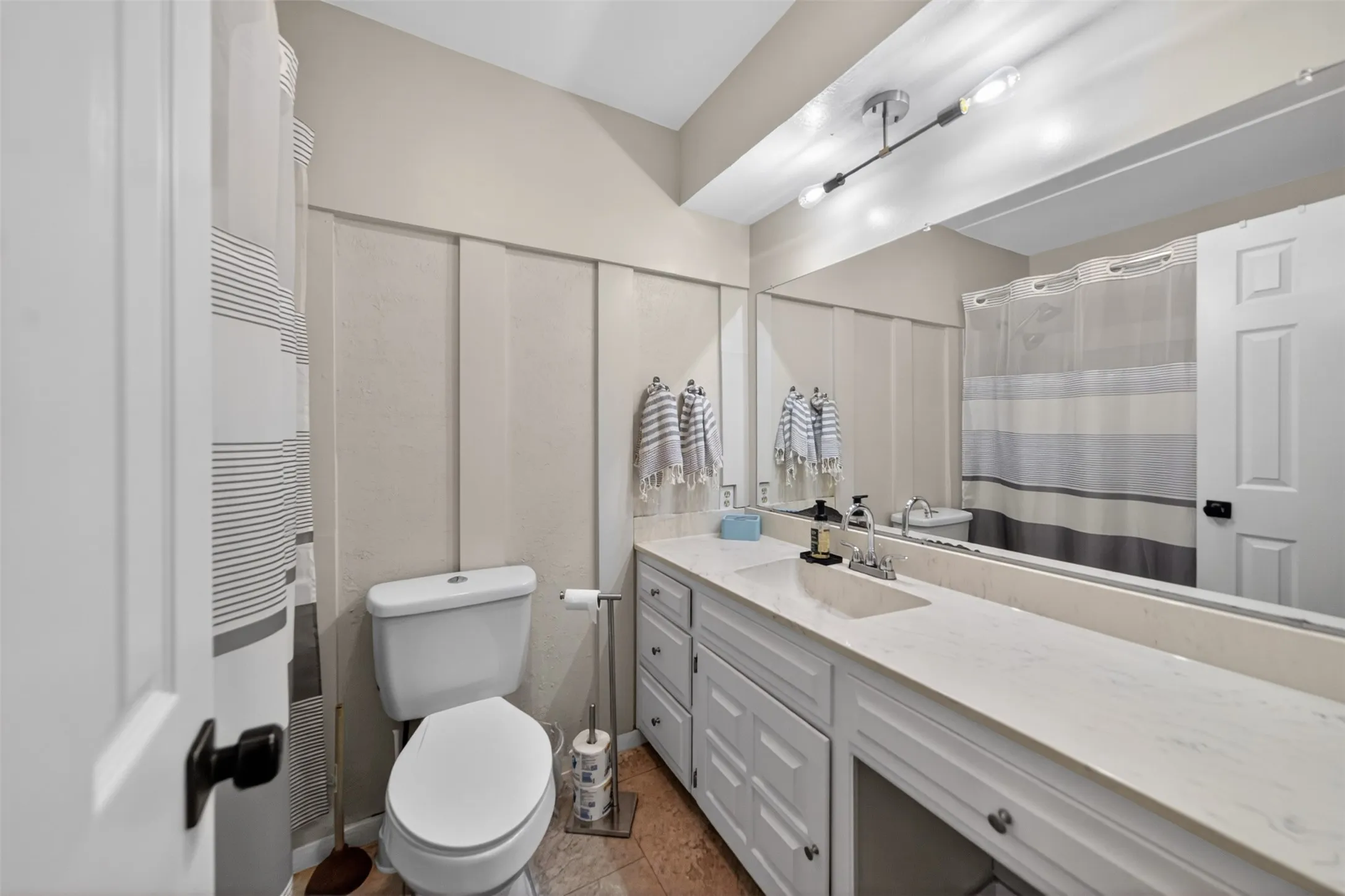 Bathroom featuring a large vanity with an integrated sink, an expansive mirror, and a two-light fixture