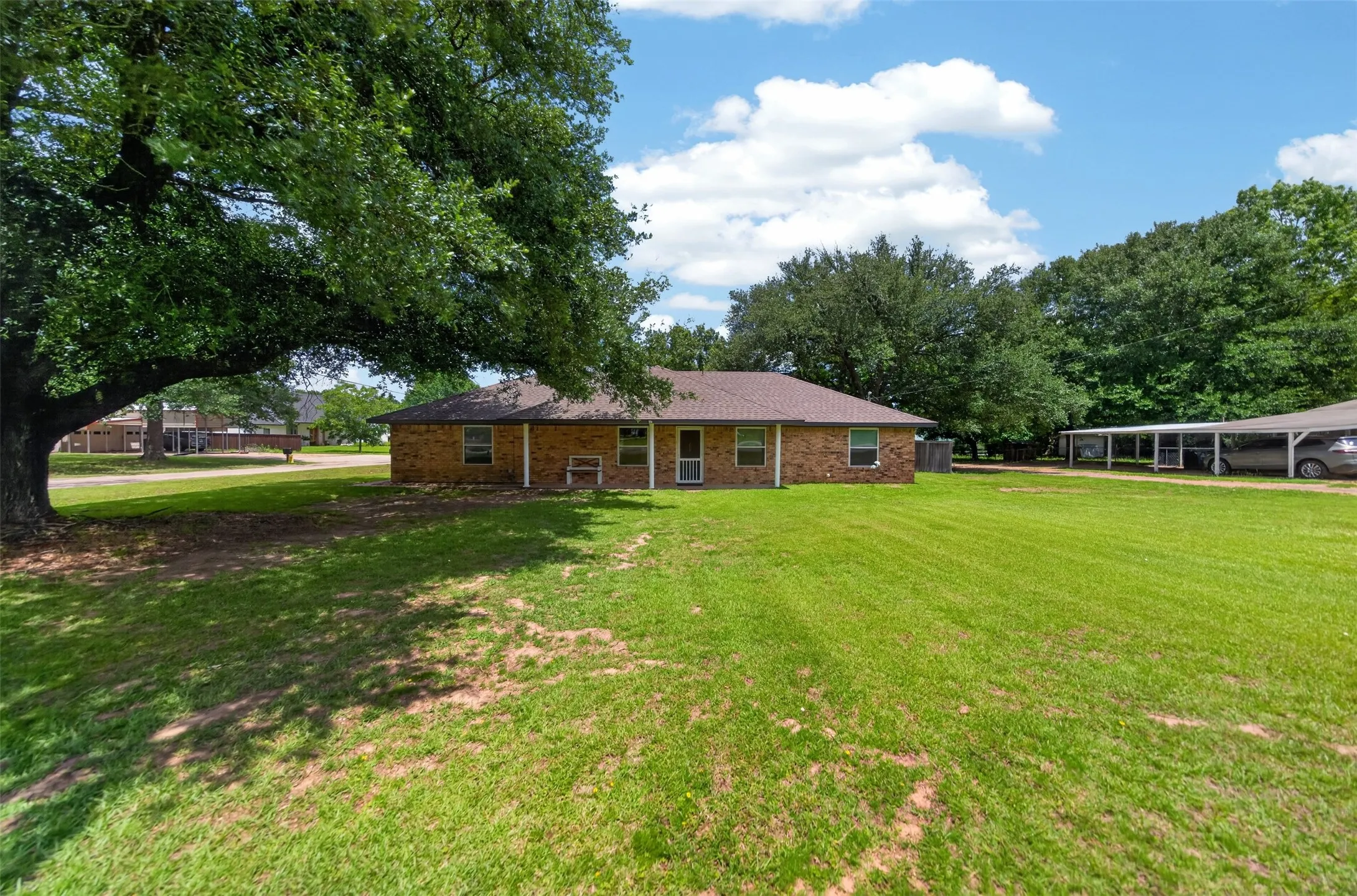 Expansive green lawn surrounds a brick exterior residence with multiple windows