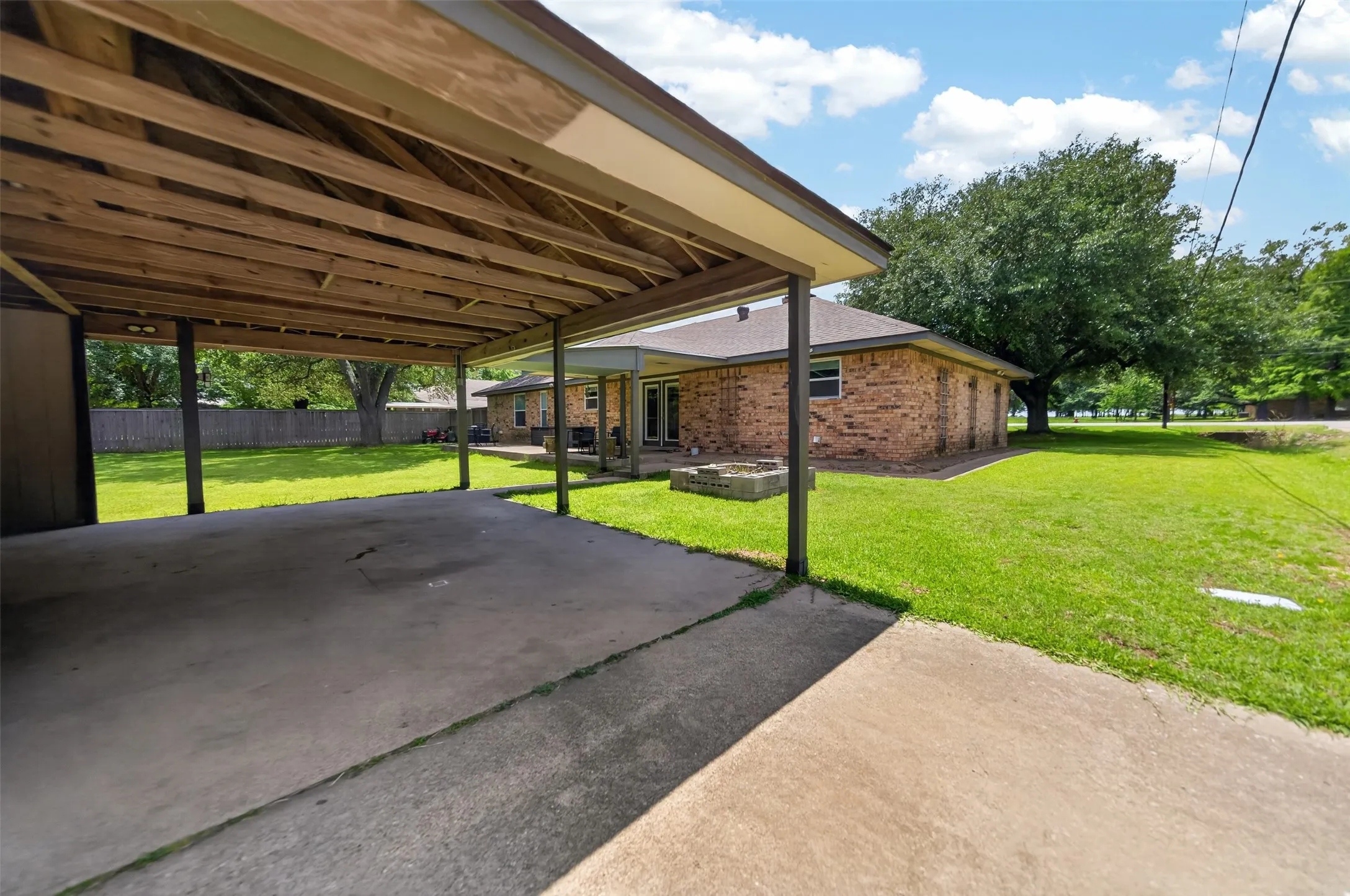Covered carport with exposed wood beam ceiling and concrete pad