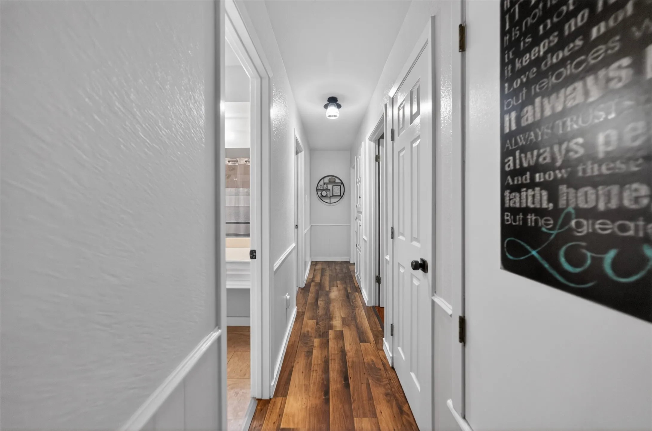 Hallway featuring wood-finish flooring and white paneled doors