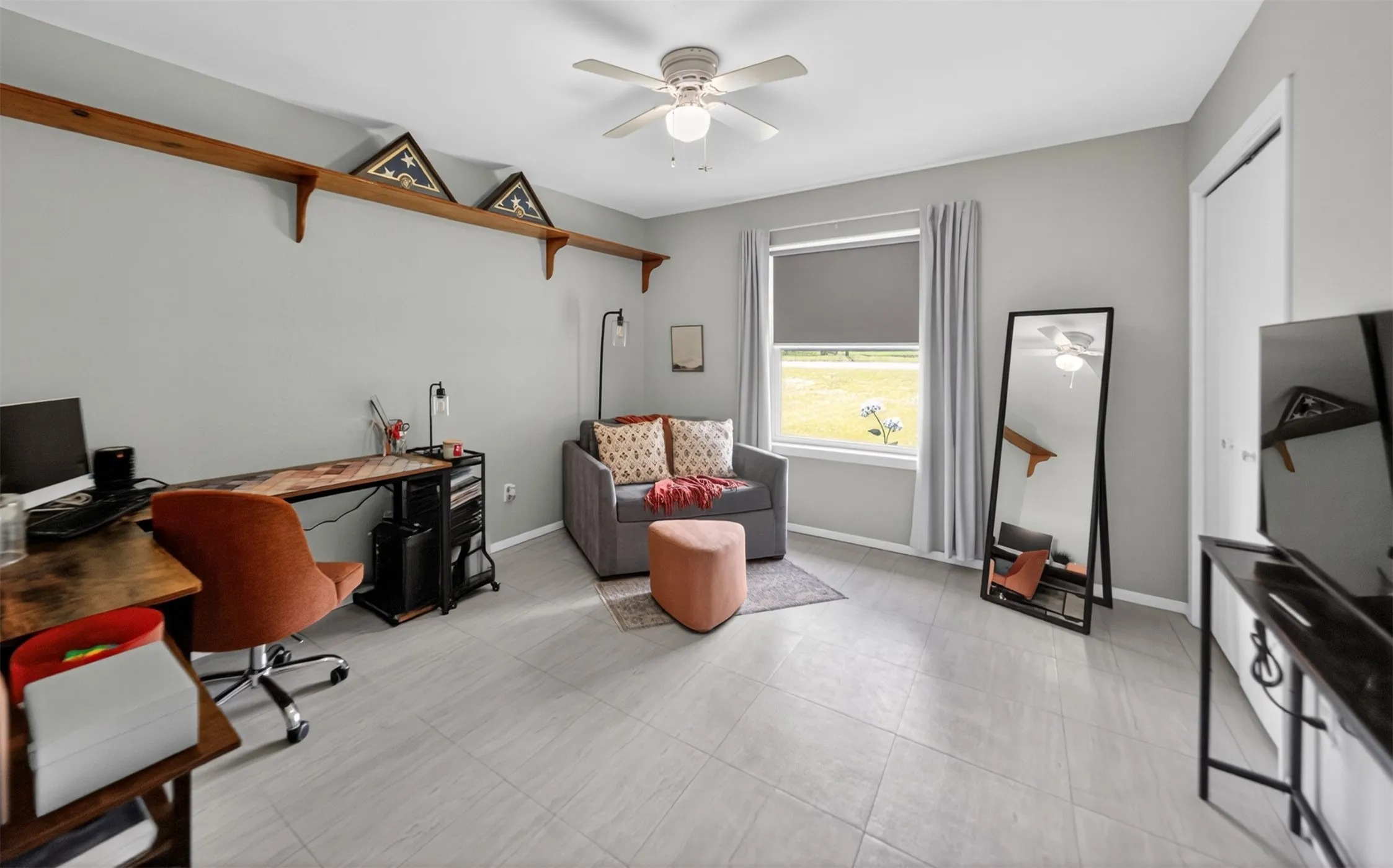 Spacious interior room featuring light-toned tile flooring, neutral wall paint, and a ceiling fan with integrated lighting