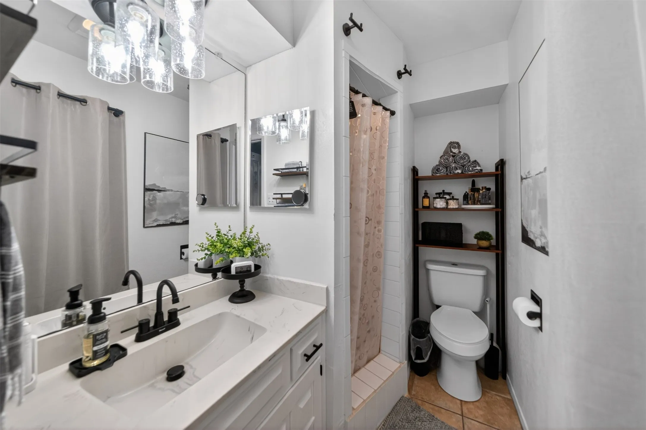 Bathroom featuring a white vanity with an integrated sink and matte black faucet, wall-mounted mirror, and a three-light fixture with clear glass shades
