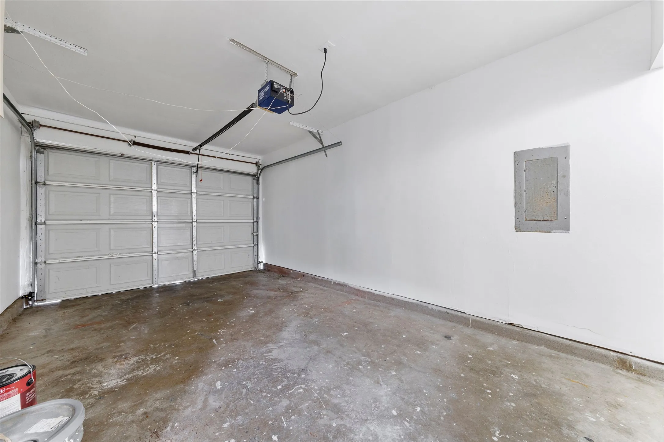 Interior garage space with a paneled overhead door, concrete flooring, and white painted walls