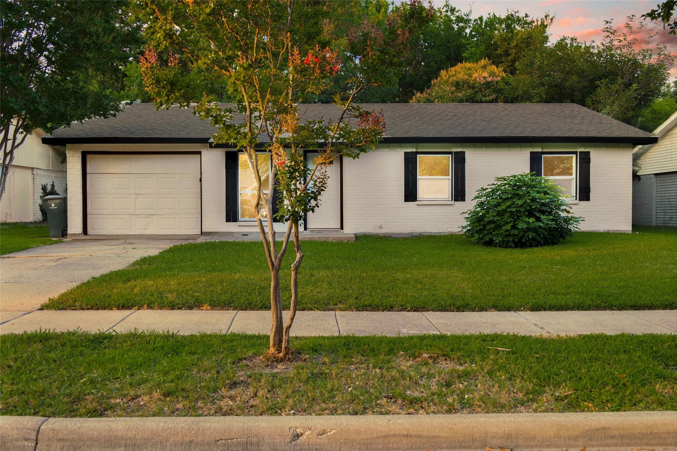 Single-story residence featuring a white brick exterior and a dark shingled roof