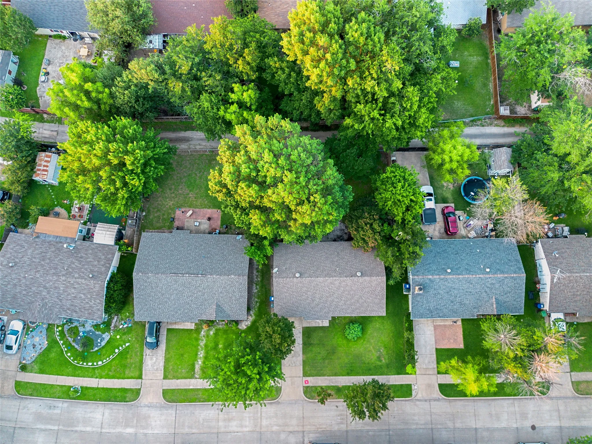 Aerial perspective showcasing multiple properties featuring shingle roofs, green lawns, and mature trees