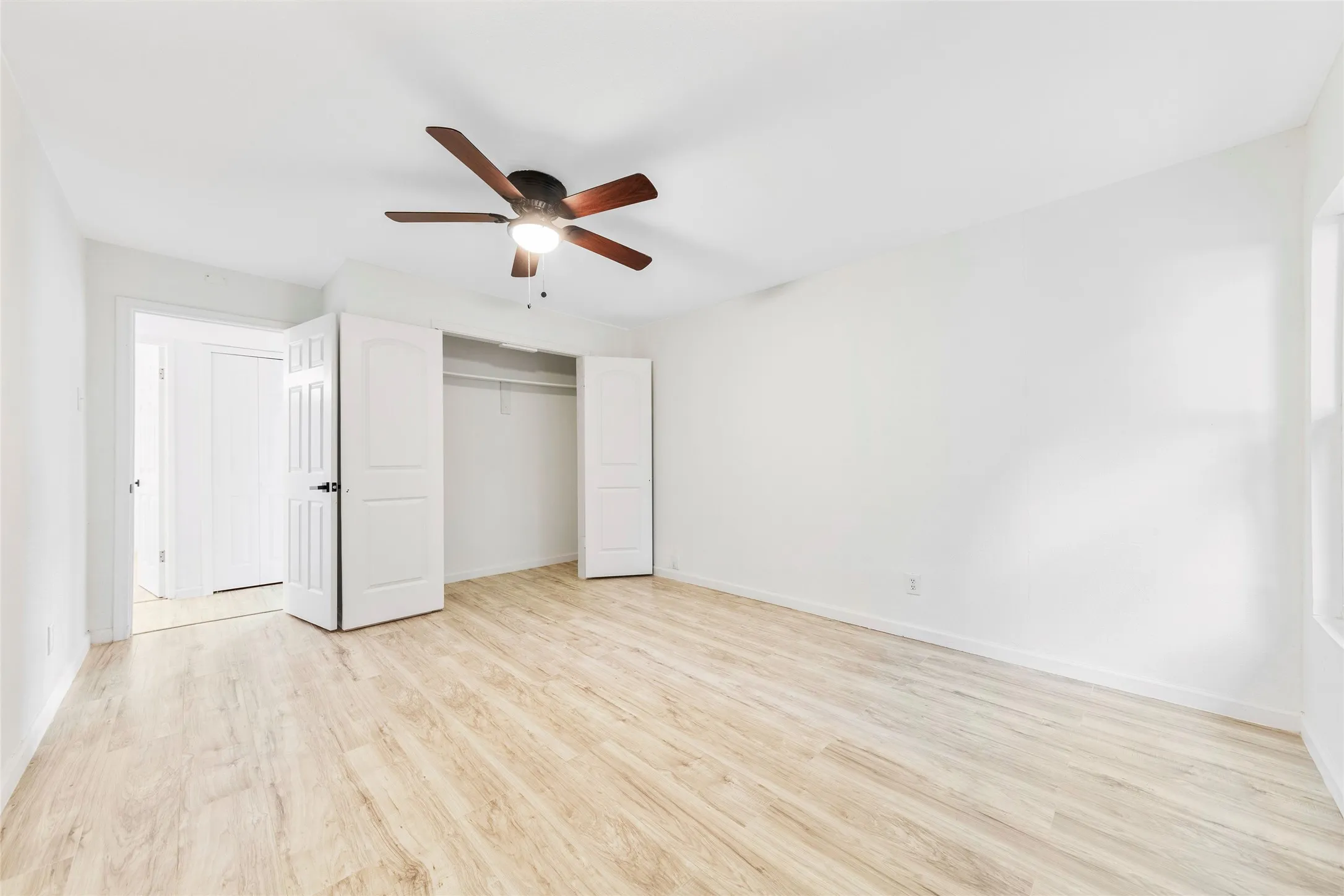 Bedroom featuring wood-finish flooring, a ceiling fan with integrated lighting, and a closet with bifold doors