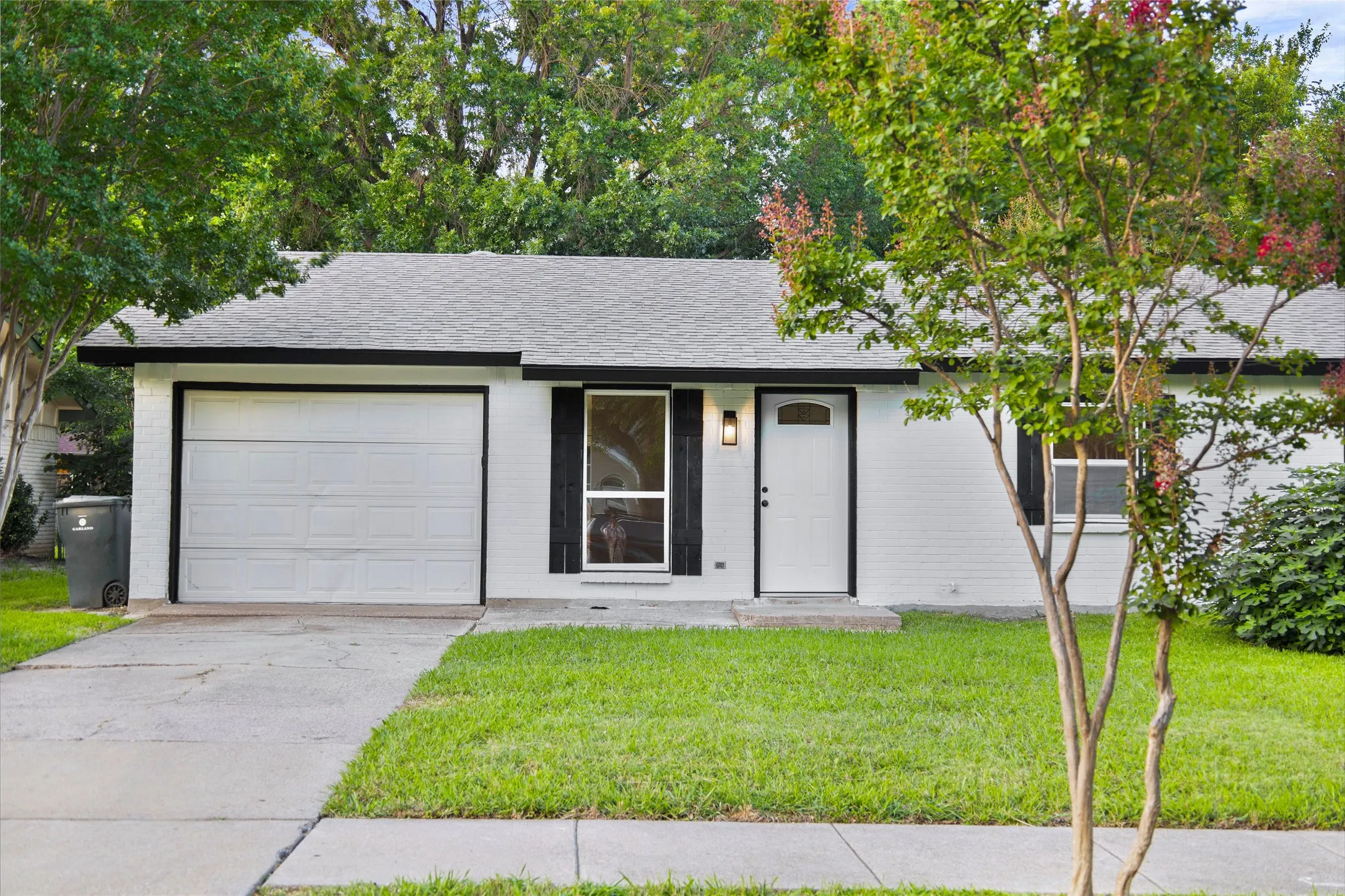 White painted brick exterior with a gray shingle roof