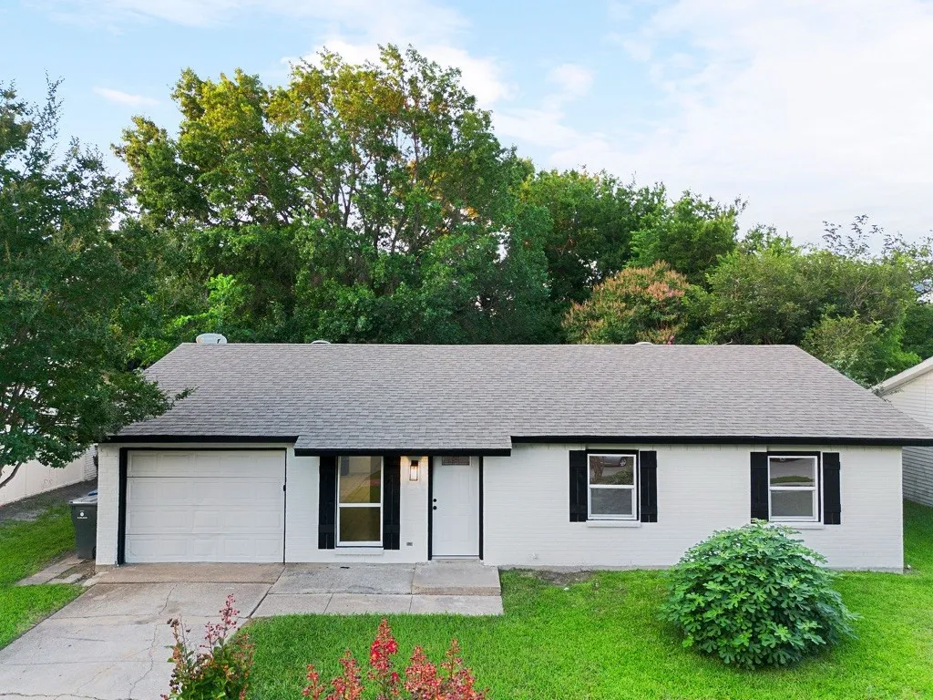 Single-story residence featuring a white painted brick exterior, a dark shingle roof, and black window shutters