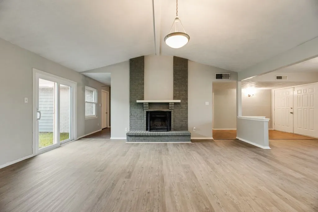 Spacious living area featuring a vaulted ceiling and wood-finish flooring