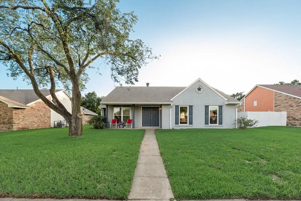 Single-story residence featuring a light gray brick exterior with dark shutters