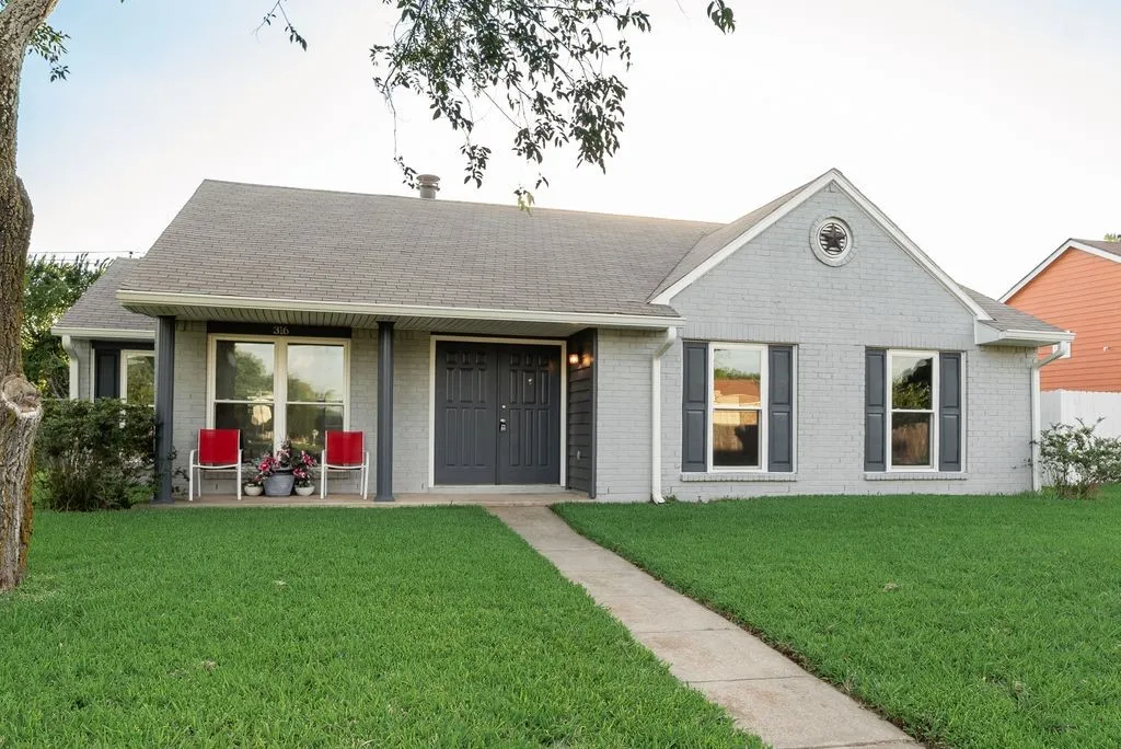 Gray brick facade with dark gray shutters and an arched entryway