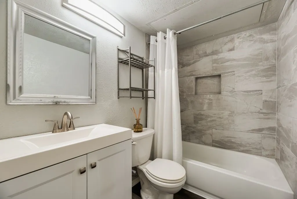 Bathroom featuring a white vanity with integrated sink, brushed nickel faucet, and a framed mirror