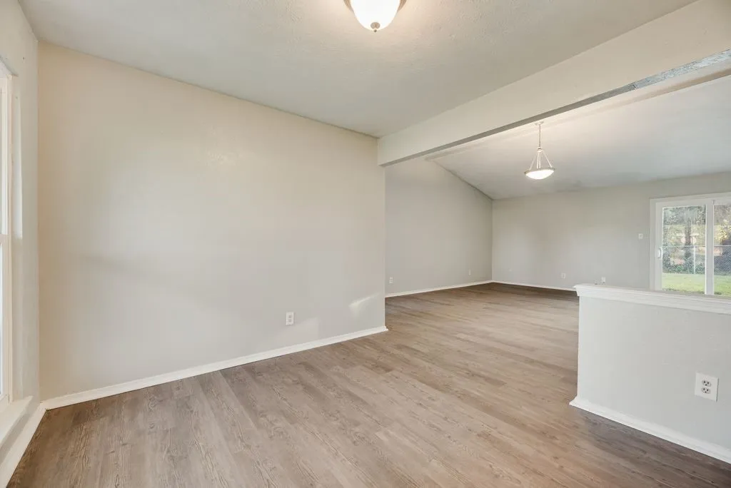 Open-concept living area featuring wood-finish flooring, vaulted ceilings, and a sliding glass door to the exterior