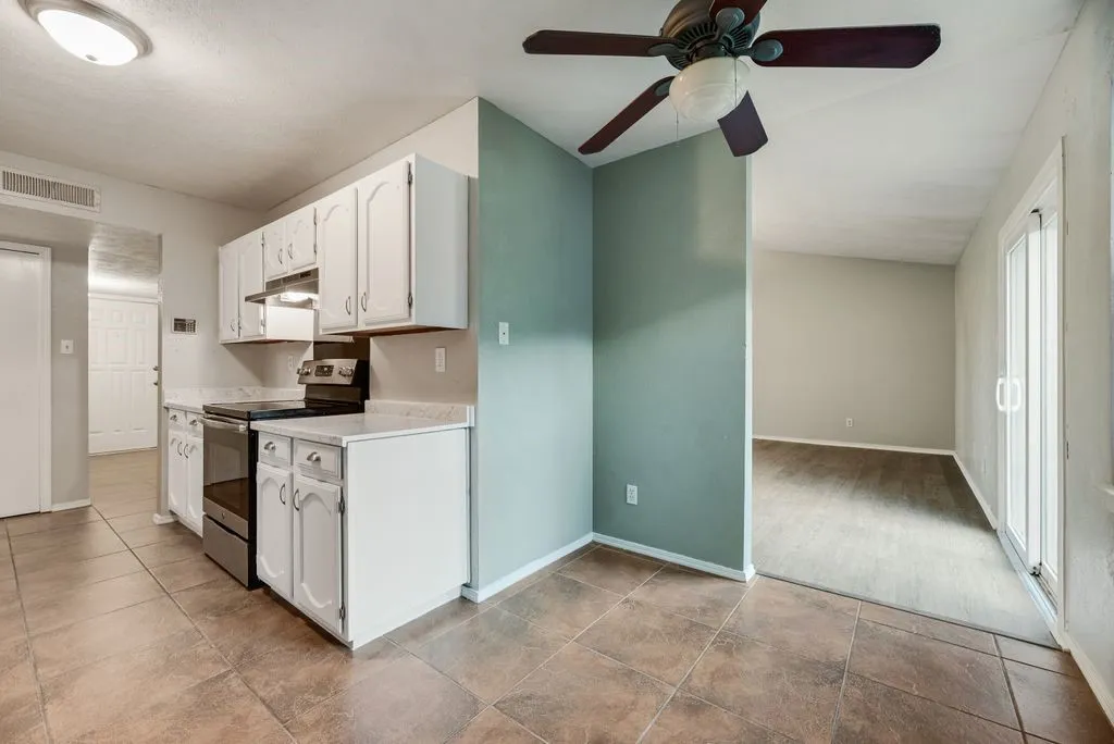 Kitchen featuring white cabinetry, dark countertop surfaces, stainless steel appliances, and brown tile flooring