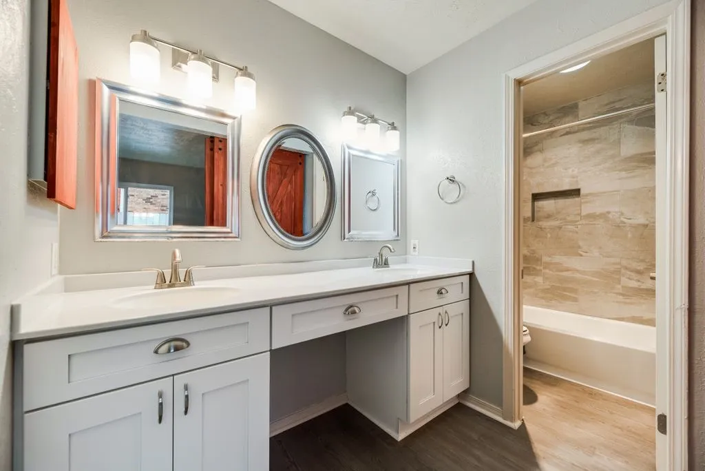 Bathroom featuring a dual vanity with white cabinetry, brushed nickel hardware, and a white countertop
